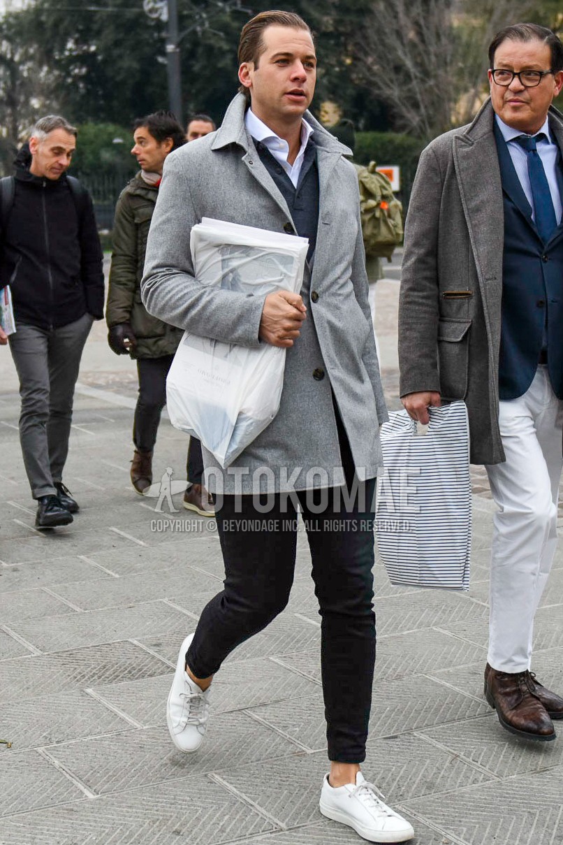 Men's winter outfit with gray plain stenkarrer coat, white plain shirt, gray plain polo shirt, black plain denim/jeans, white low-cut sneakers.