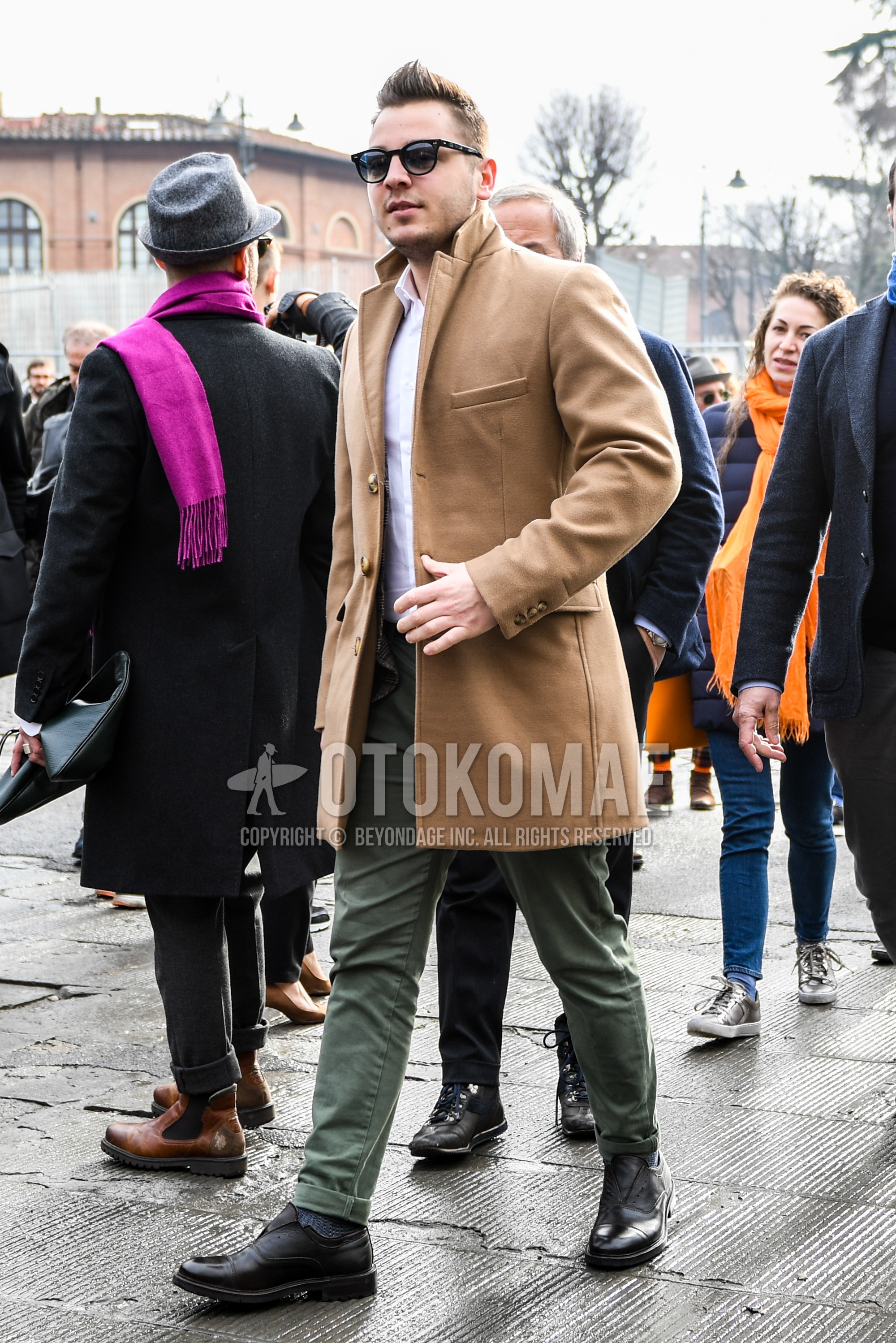 Men's winter outfit with plain sunglasses, brown plain chester coat, white plain shirt, green plain chinos, gray plain socks, black  leather shoes.