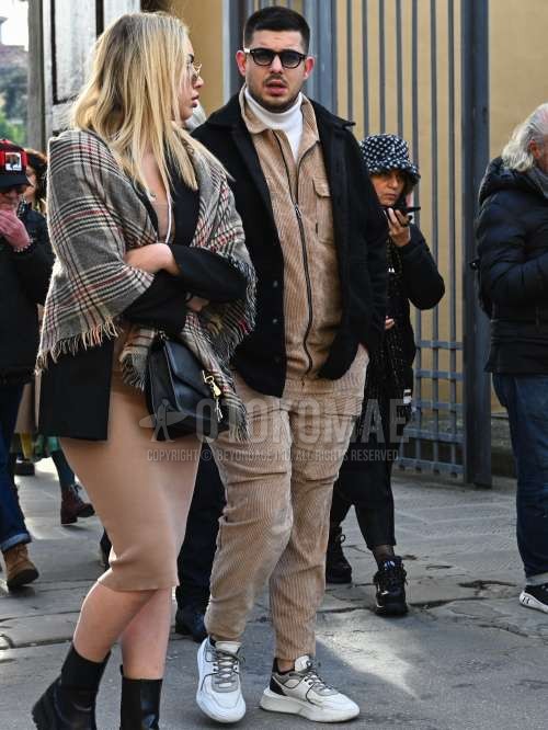 黒無地のサングラス、黒無地のフリースジャケット、白無地のタートルネックニット、白ローカットのスニーカー、ベージュ無地のカジュアルセットアップを合わせた秋冬のメンズコーデ・着こなし。