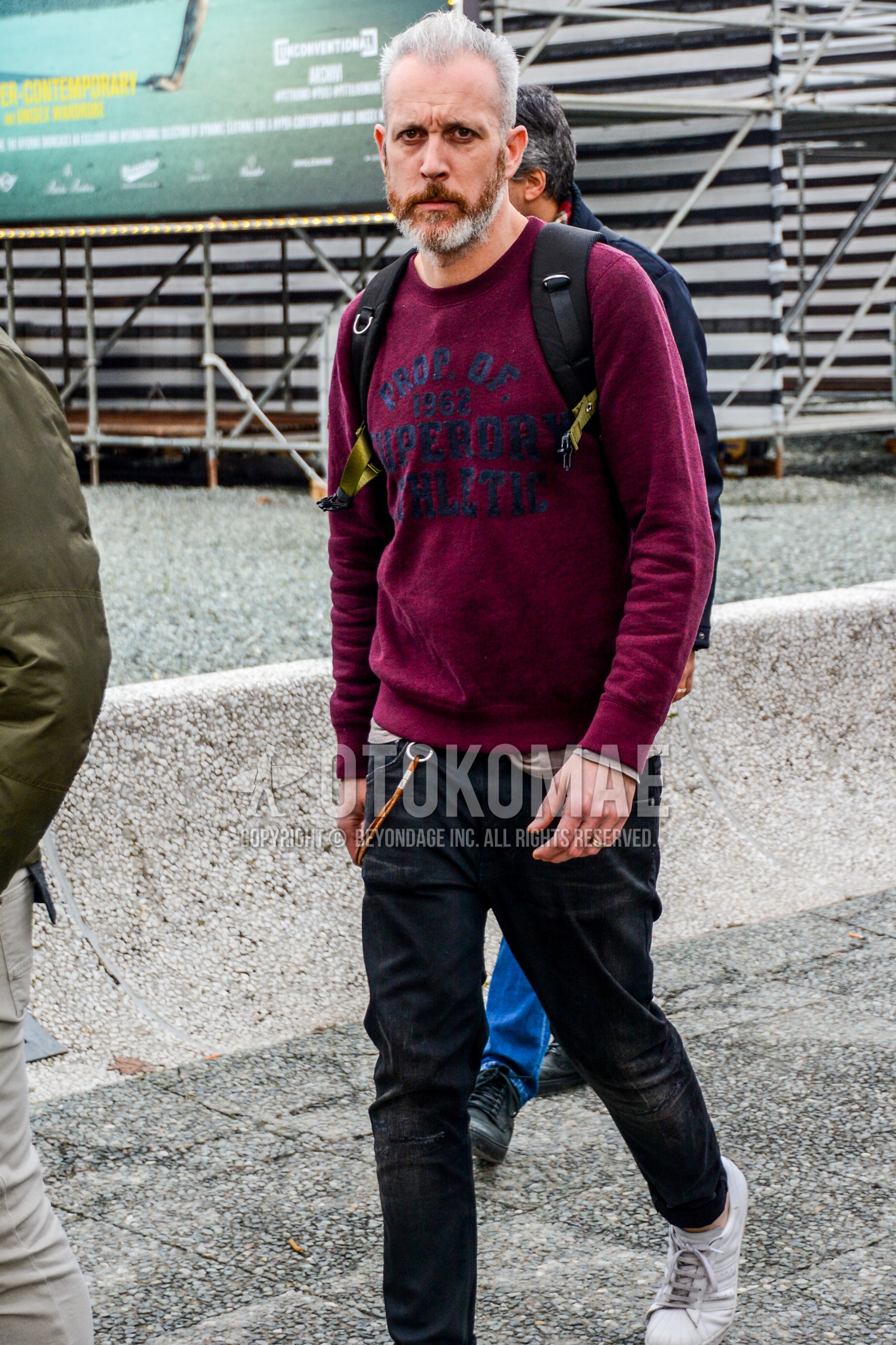 Men's spring autumn outfit with red lettered sweatshirt, black plain denim/jeans, white low-cut sneakers.