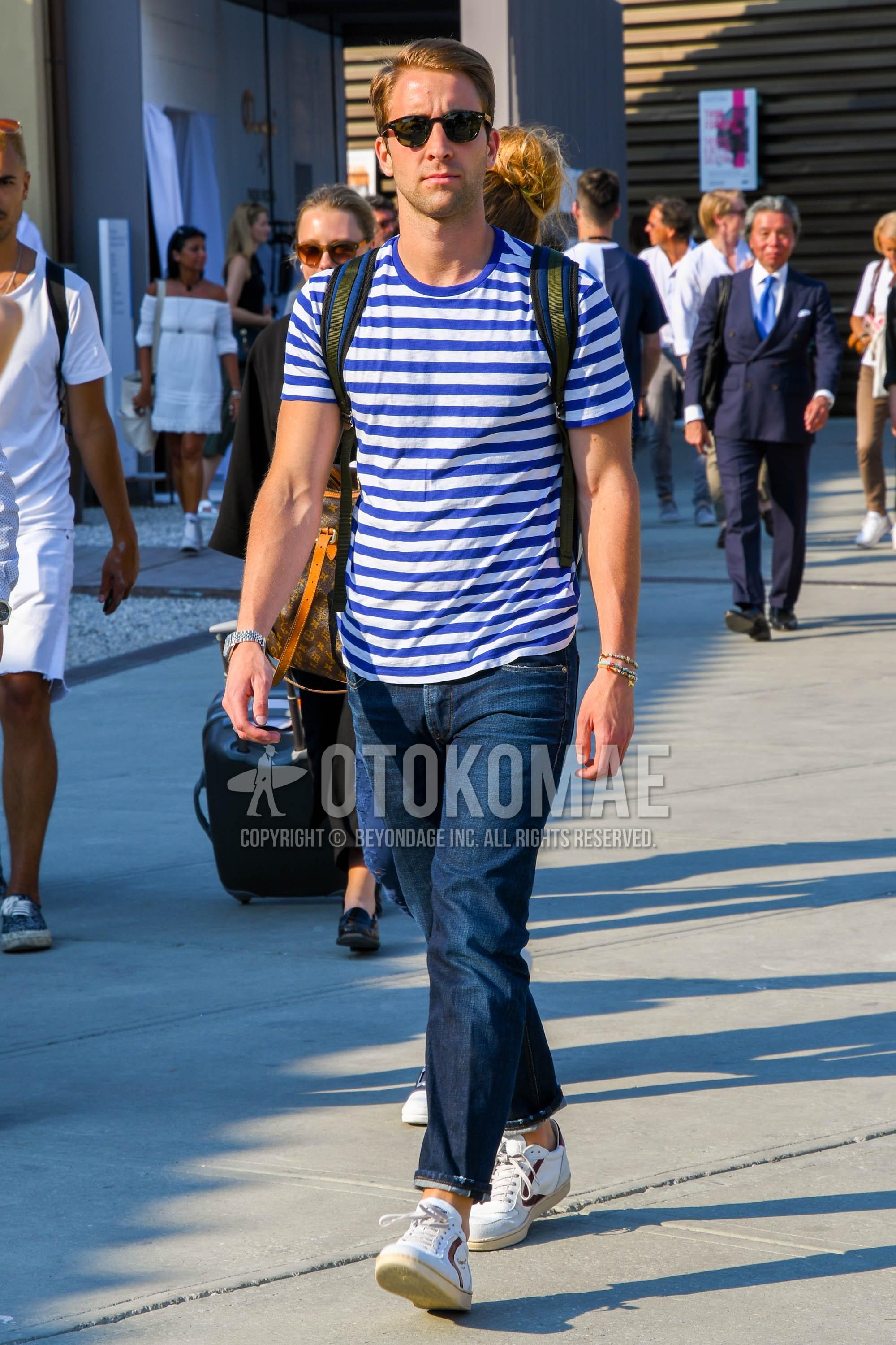 Men's summer outfit with plain sunglasses, white blue horizontal stripes t-shirt, navy plain denim/jeans, white low-cut sneakers.