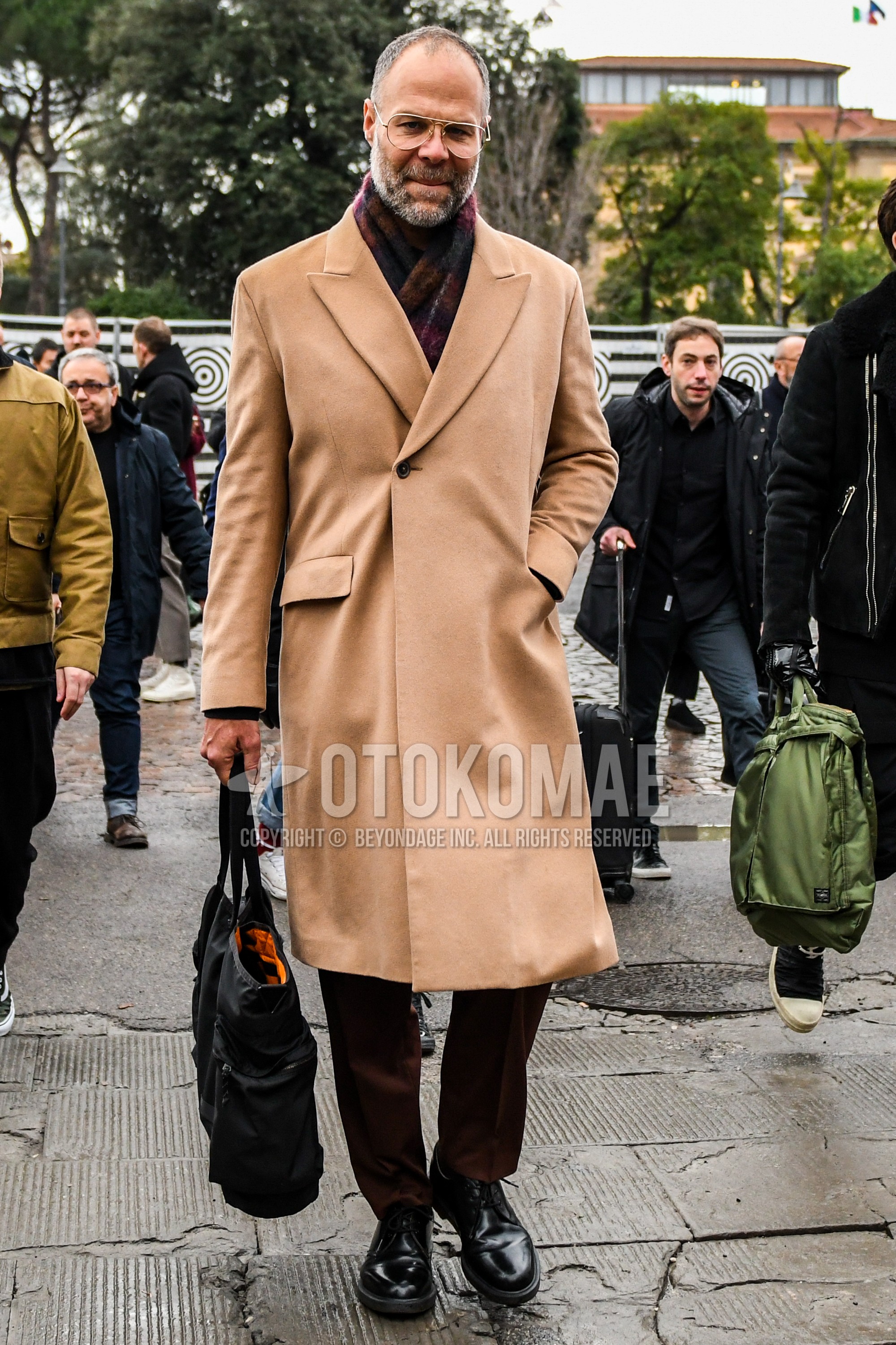 Men's winter outfit with plain glasses, red check scarf, brown plain chester coat, brown plain slacks, black plain toe leather shoes, black plain tote bag.