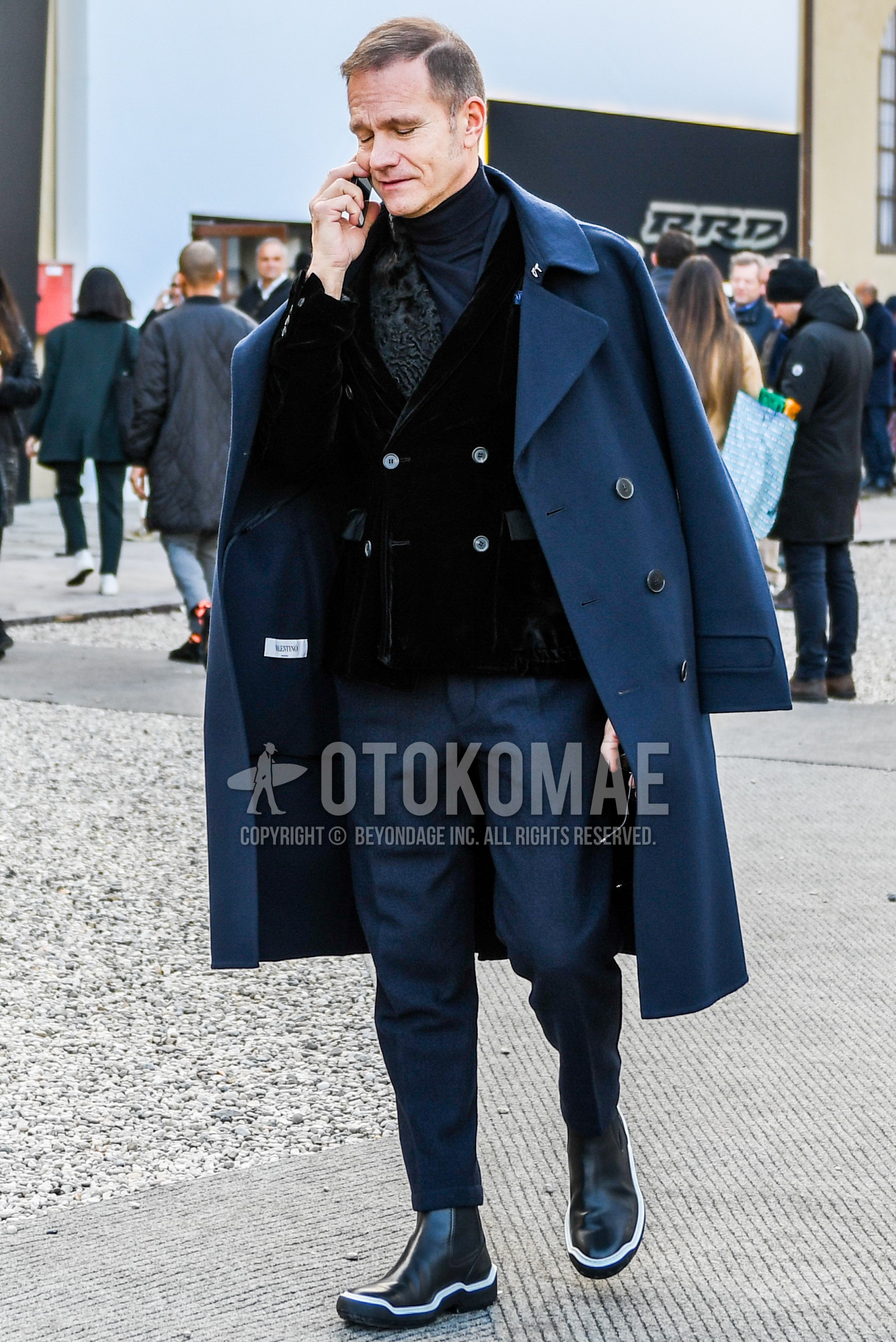 Men's winter outfit with blue plain ulster coat, black plain tailored jacket, dark gray plain turtleneck knit, dark gray plain slacks, black  boots.