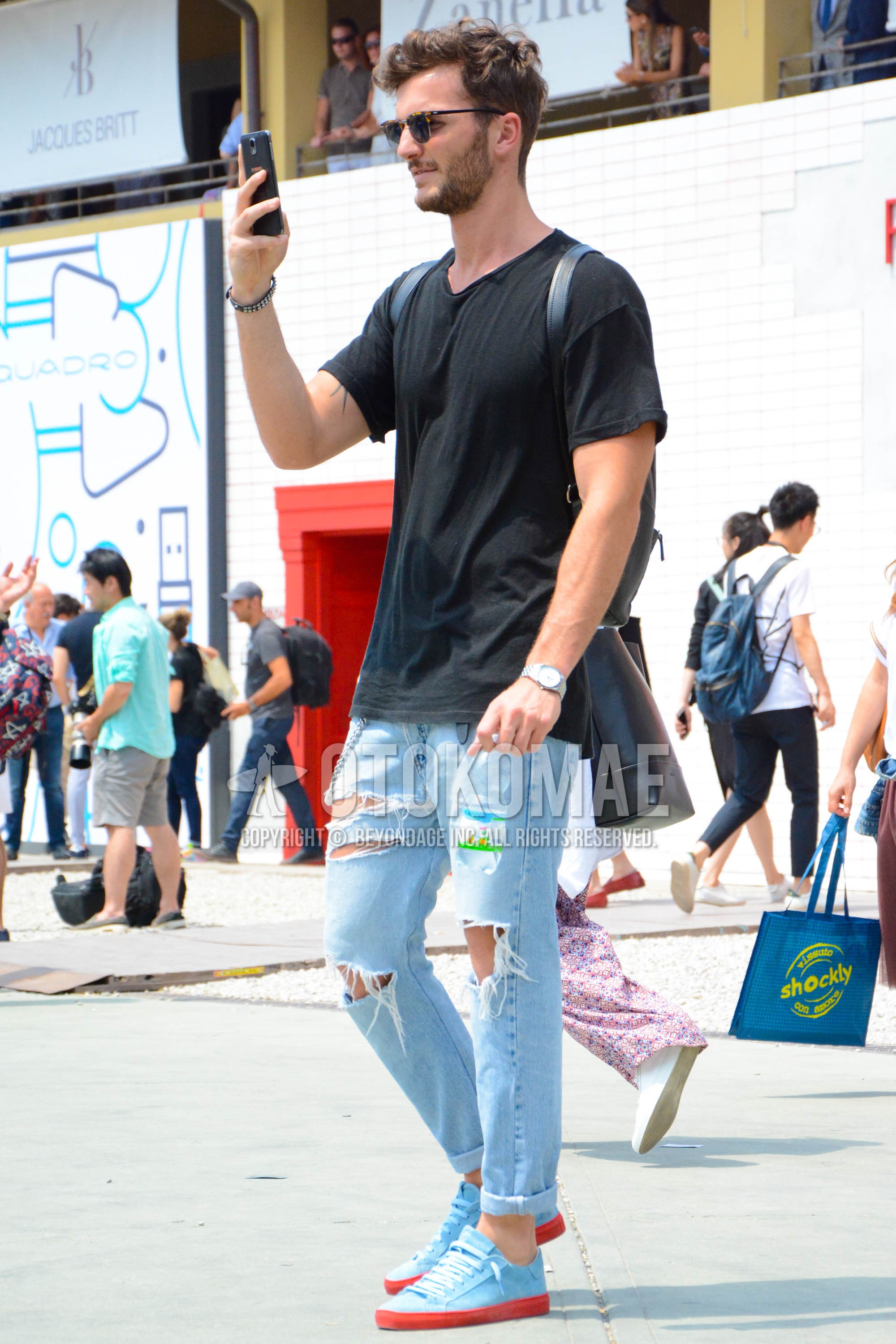 Men's summer outfit with plain sunglasses, black plain t-shirt, light blue plain damaged jeans, light blue low-cut sneakers.