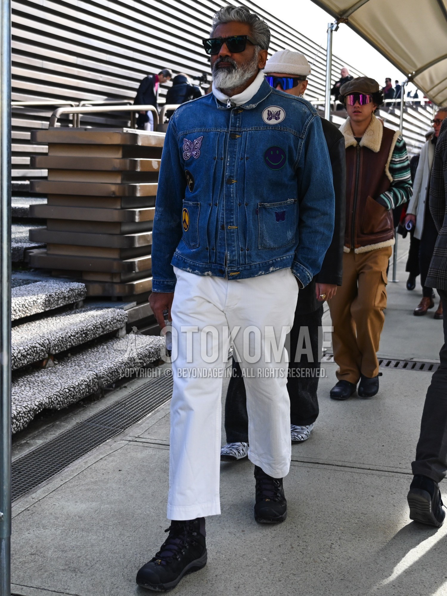 Men's autumn winter outfit with black plain sunglasses, blue plain denim jacket, white plain down jacket, white plain cotton pants, black high-cut sneakers.