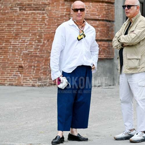 黒無地のサングラス、オレンジ・水色・イエロー無地のスカーフ、白無地のシャツ、ブルー・黒チェックのスラックス、黒コインローファーの革靴を合わせた夏のメンズコーデ・着こなし。