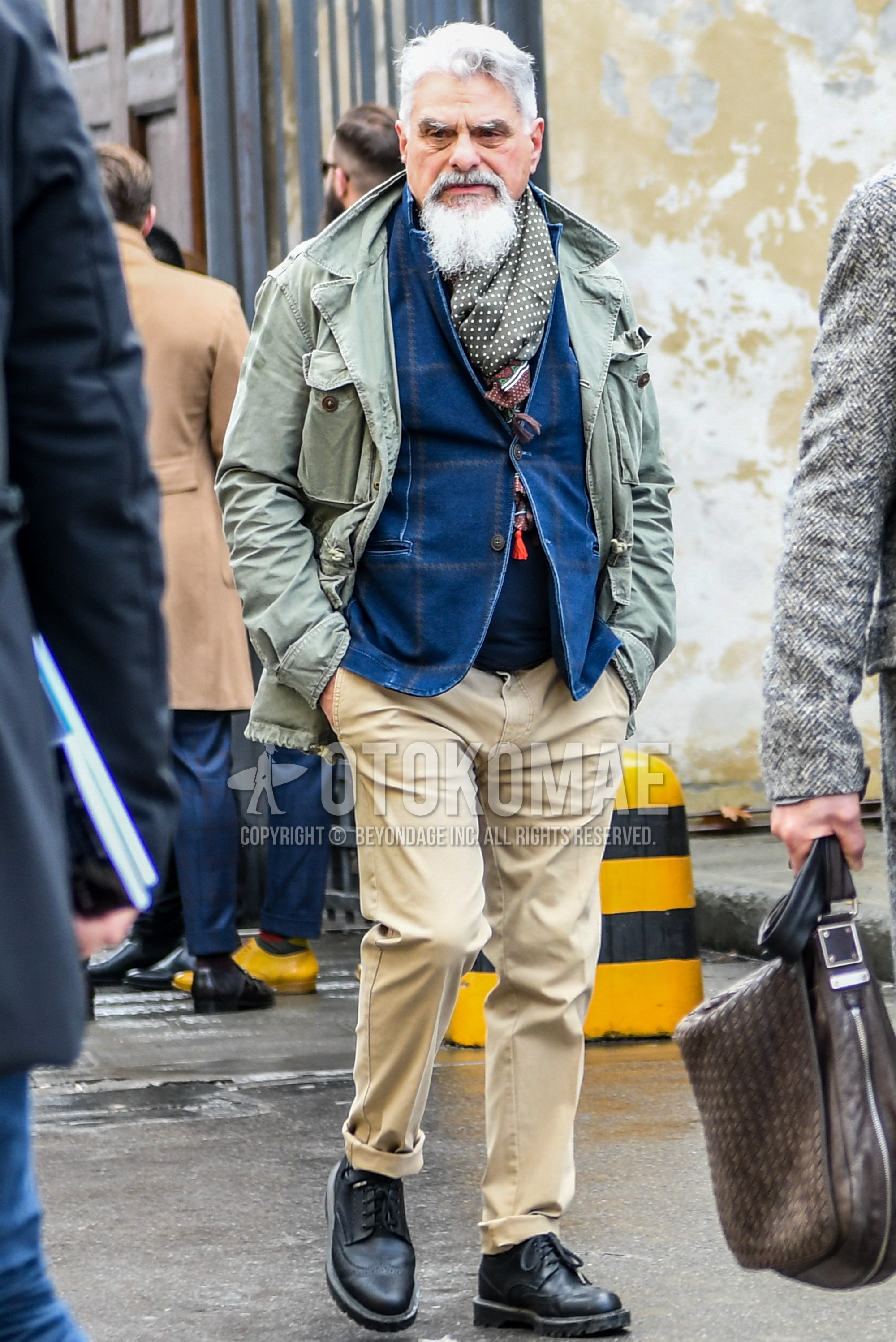 Men's winter outfit with green dots scarf, olive green plain M-65, blue check tailored jacket, navy plain sweater, beige plain chinos, black monk shoes leather shoes.