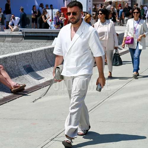 ブラウンべっ甲のサングラス、無地のシャツ、白無地のスラックス、白レザーサンダル、白バッグのサコッシュを合わせた夏春のメンズコーデ・着こなし。