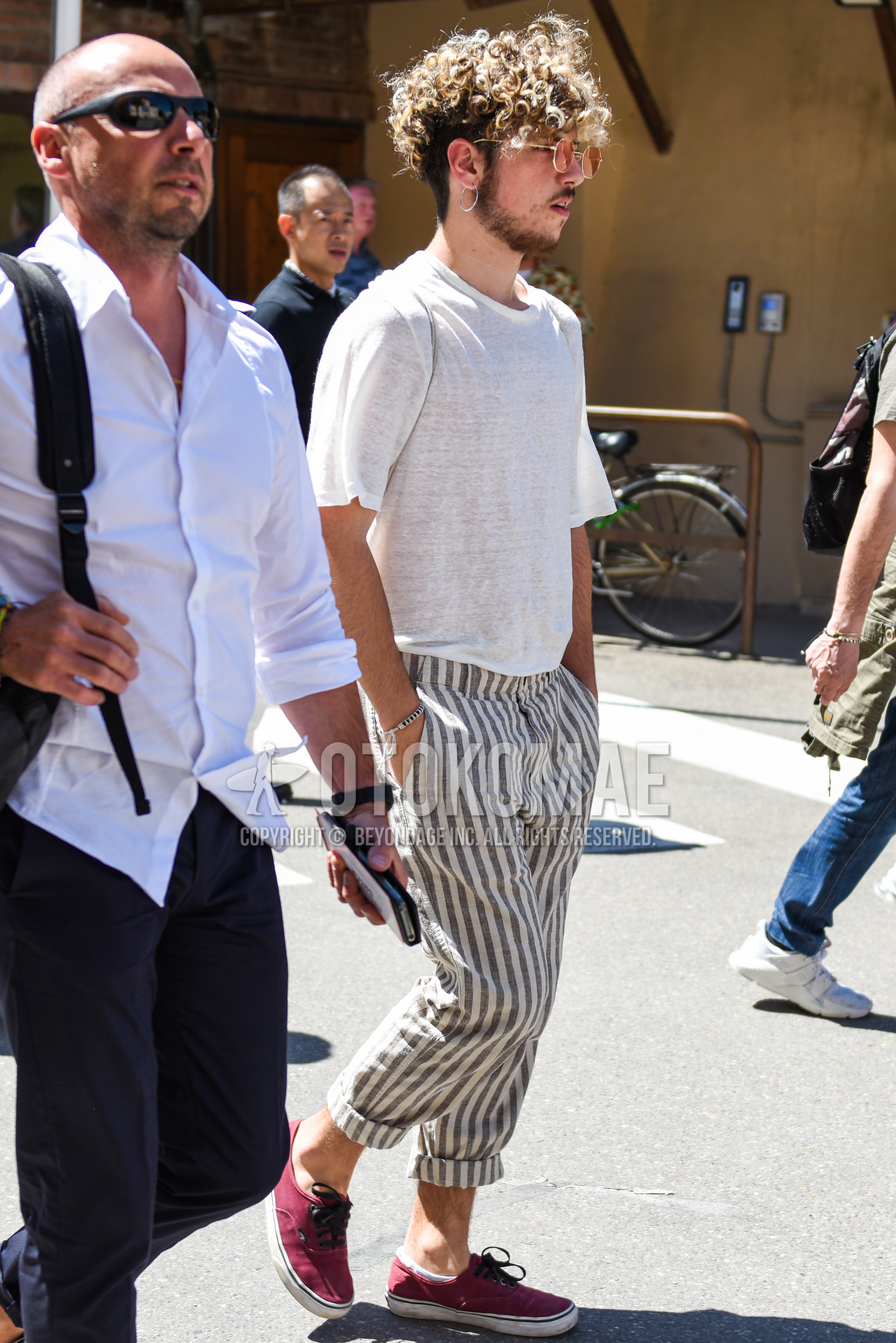 Men's summer outfit with red plain sunglasses, white plain t-shirt, white gray stripes slacks, red low-cut sneakers.