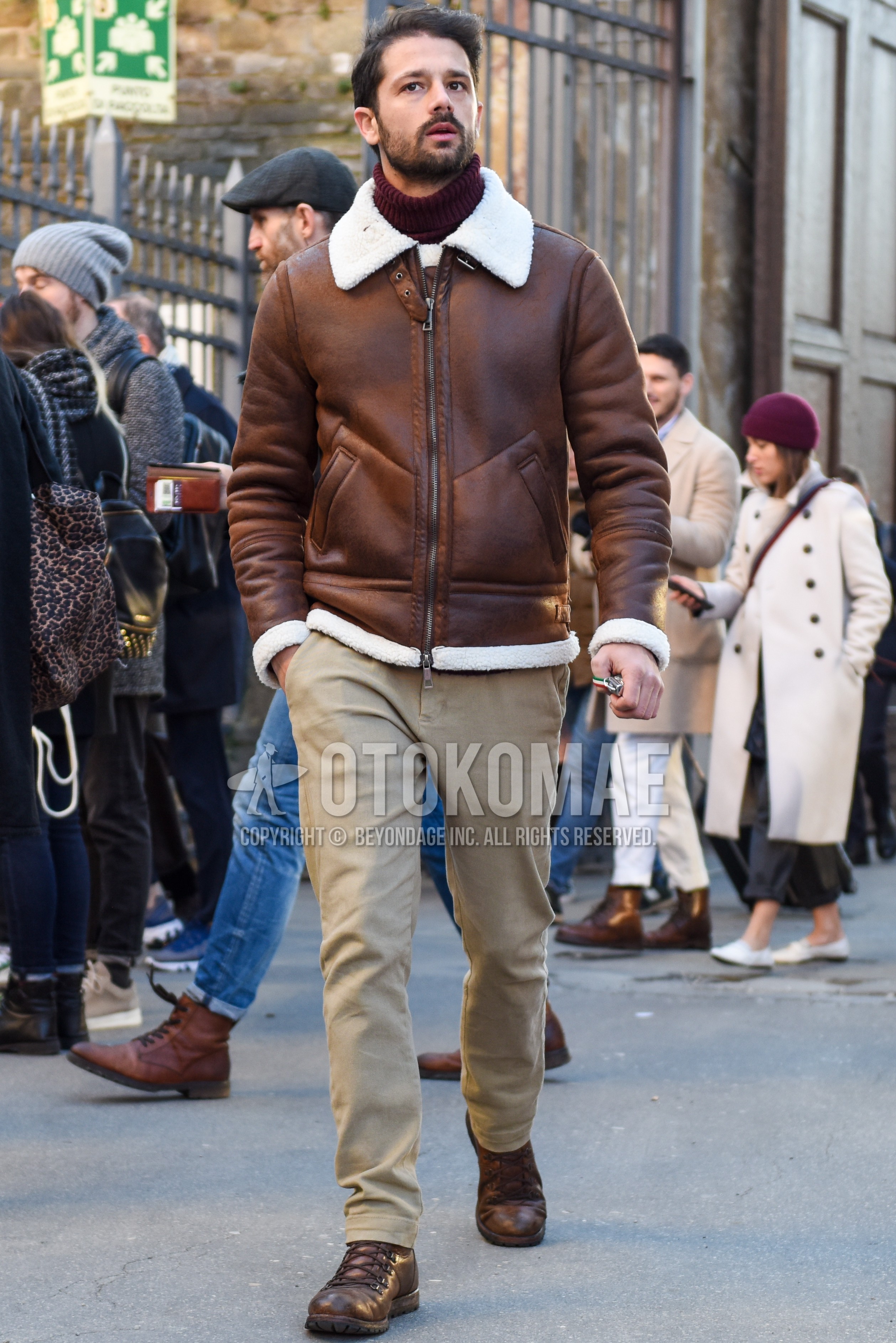 Men's autumn winter outfit with brown plain leather jacket, brown plain military jacket, brown plain turtleneck knit, beige plain chinos, brown  boots.