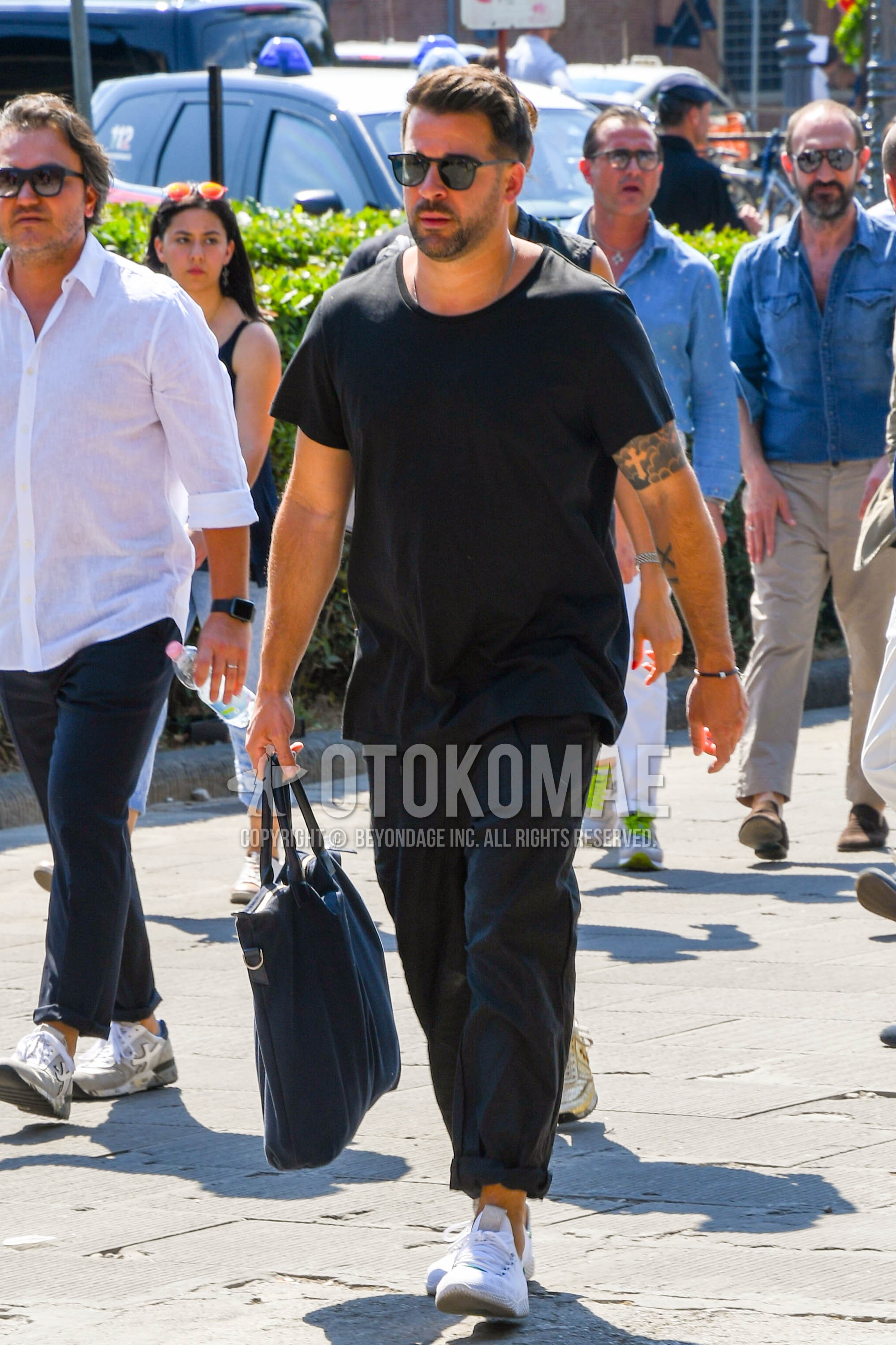 Men's summer outfit with plain sunglasses, black plain t-shirt, black plain wide pants, white low-cut sneakers, black plain briefcase/handbag.