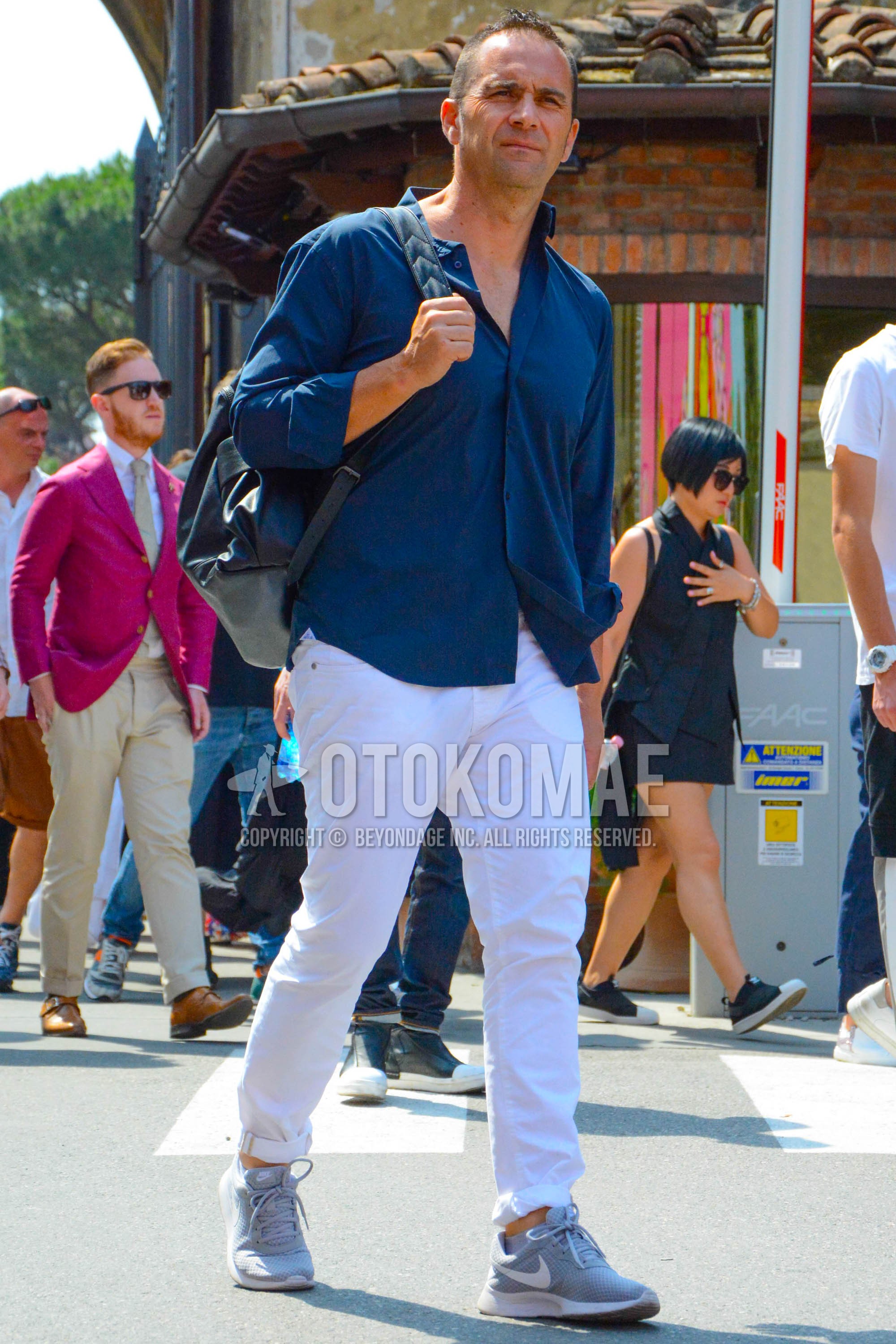 Men's spring summer outfit with navy plain shirt, white plain denim/jeans, gray low-cut sneakers, black plain backpack.