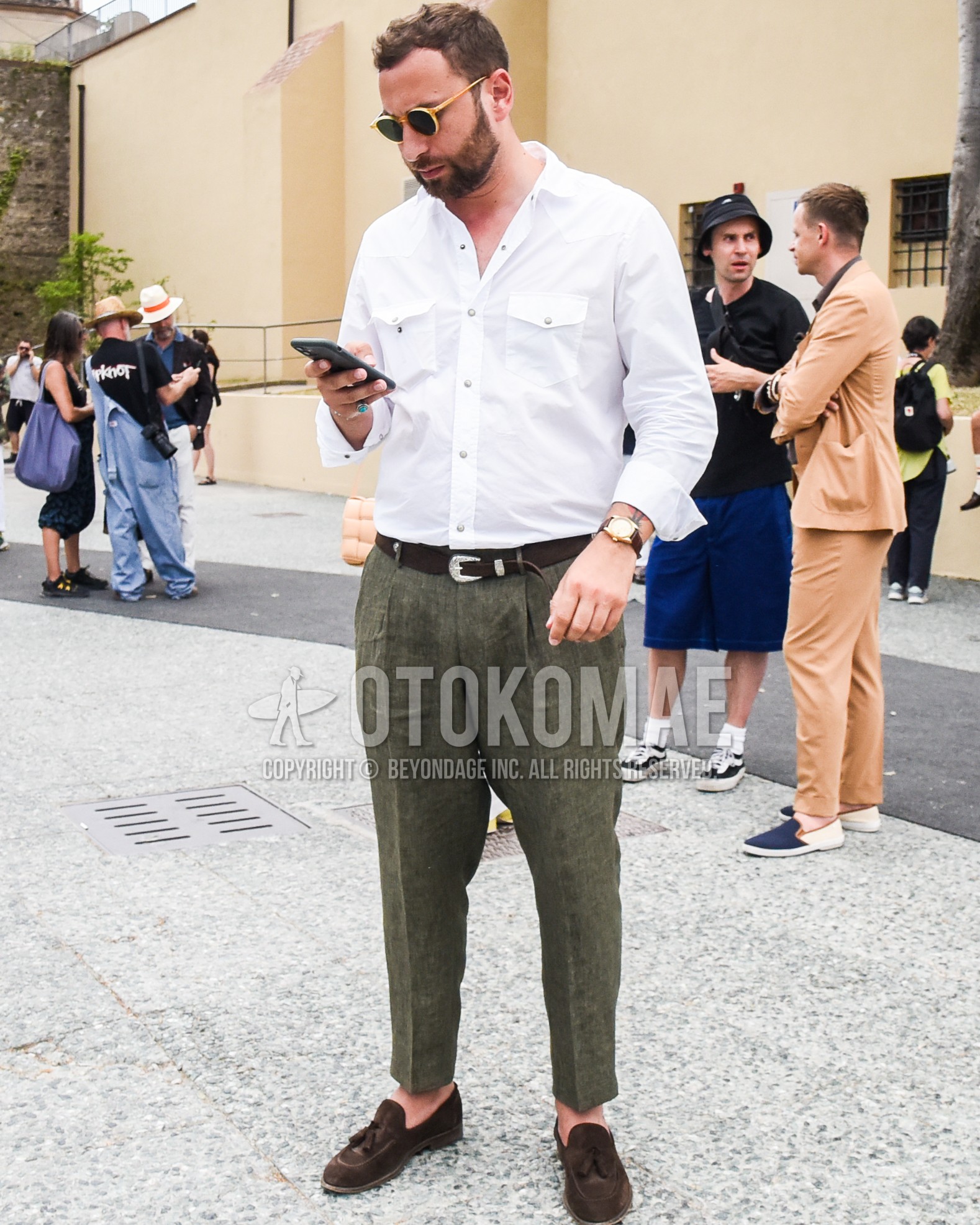 Men's spring summer outfit with white plain shirt, brown plain leather belt, olive green plain slacks, brown tassel loafers leather shoes, brown suede shoes leather shoes.