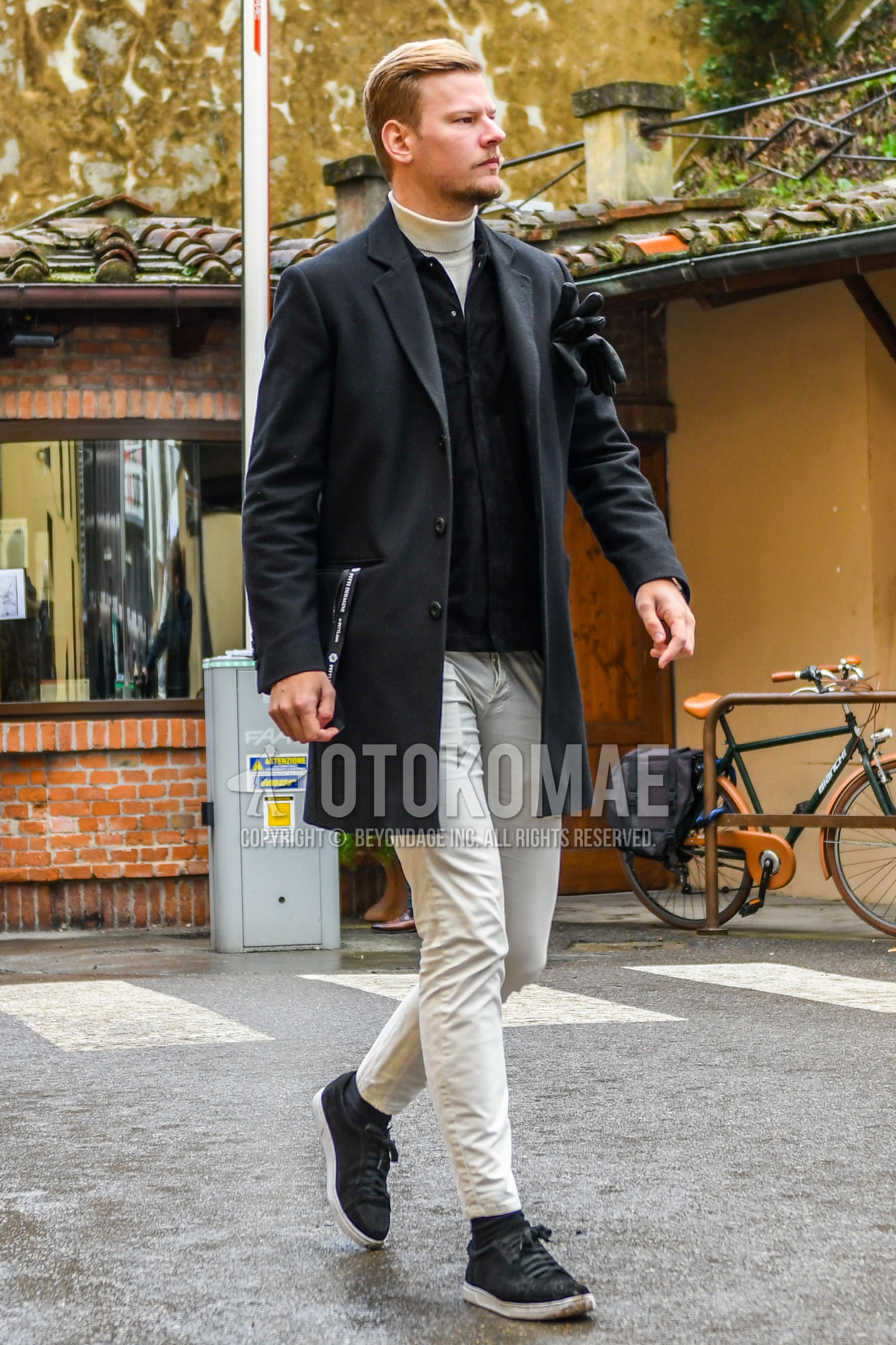 Men's winter outfit with dark gray plain chester coat, black tops/innerwear shirt, white plain turtleneck knit, white plain chinos, black plain socks, black low-cut sneakers.