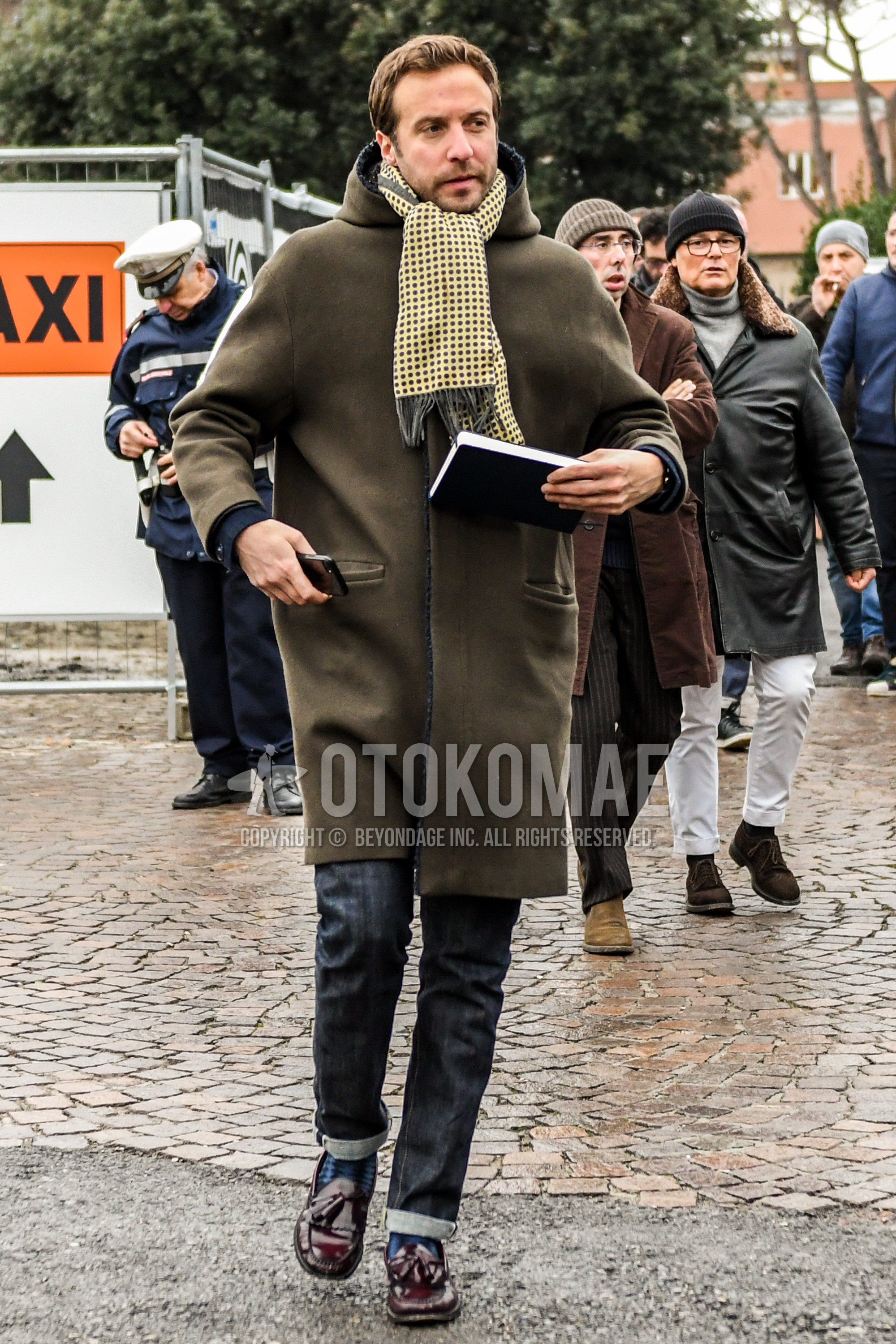 Men's autumn winter outfit with yellow dots scarf, olive green plain hooded coat, black plain denim/jeans, navy socks socks, brown tassel loafers leather shoes.