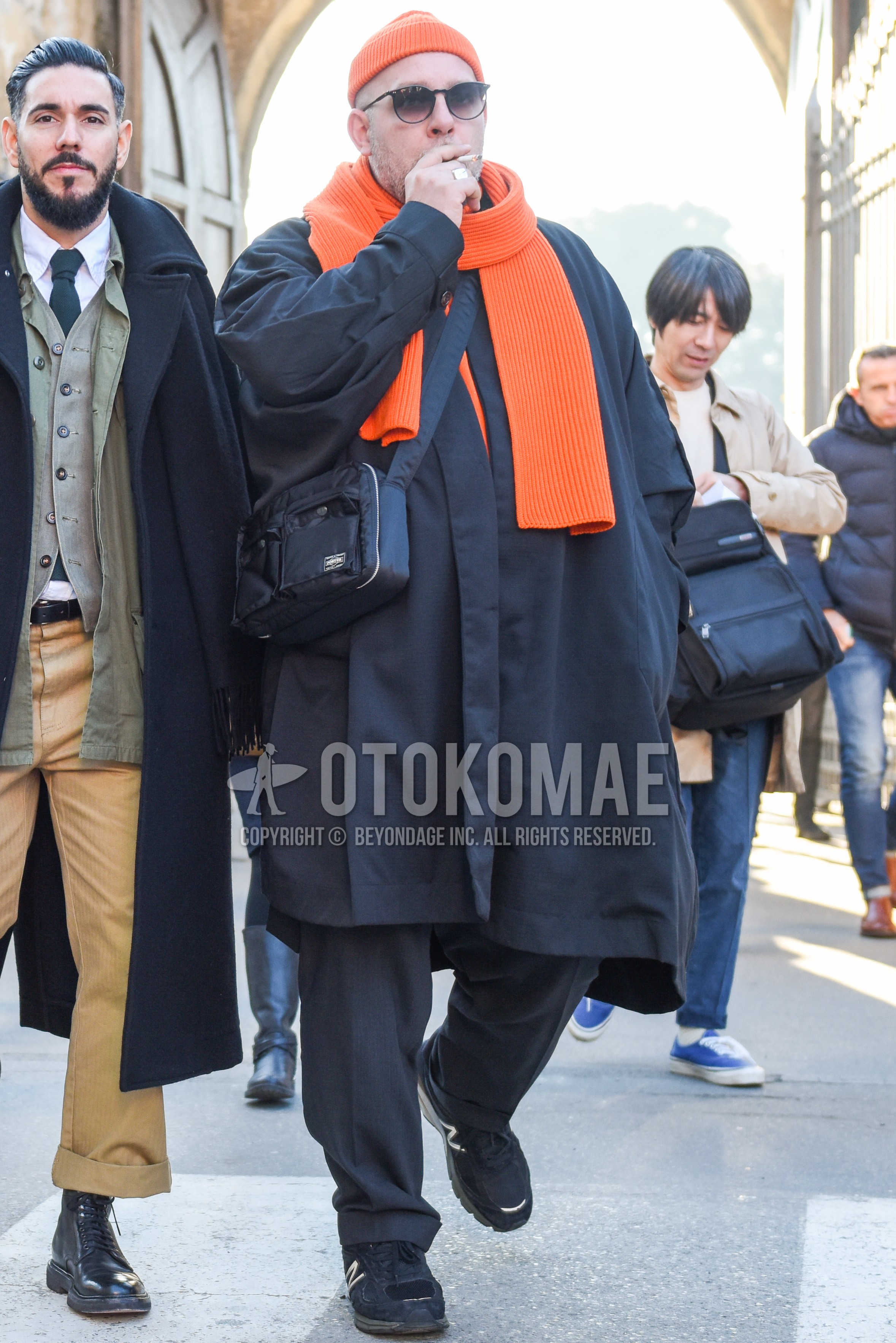 Men's autumn winter outfit with orange plain knit cap, black plain sunglasses, orange plain scarf, gray plain slacks, black low-cut sneakers, black plain shoulder bag.