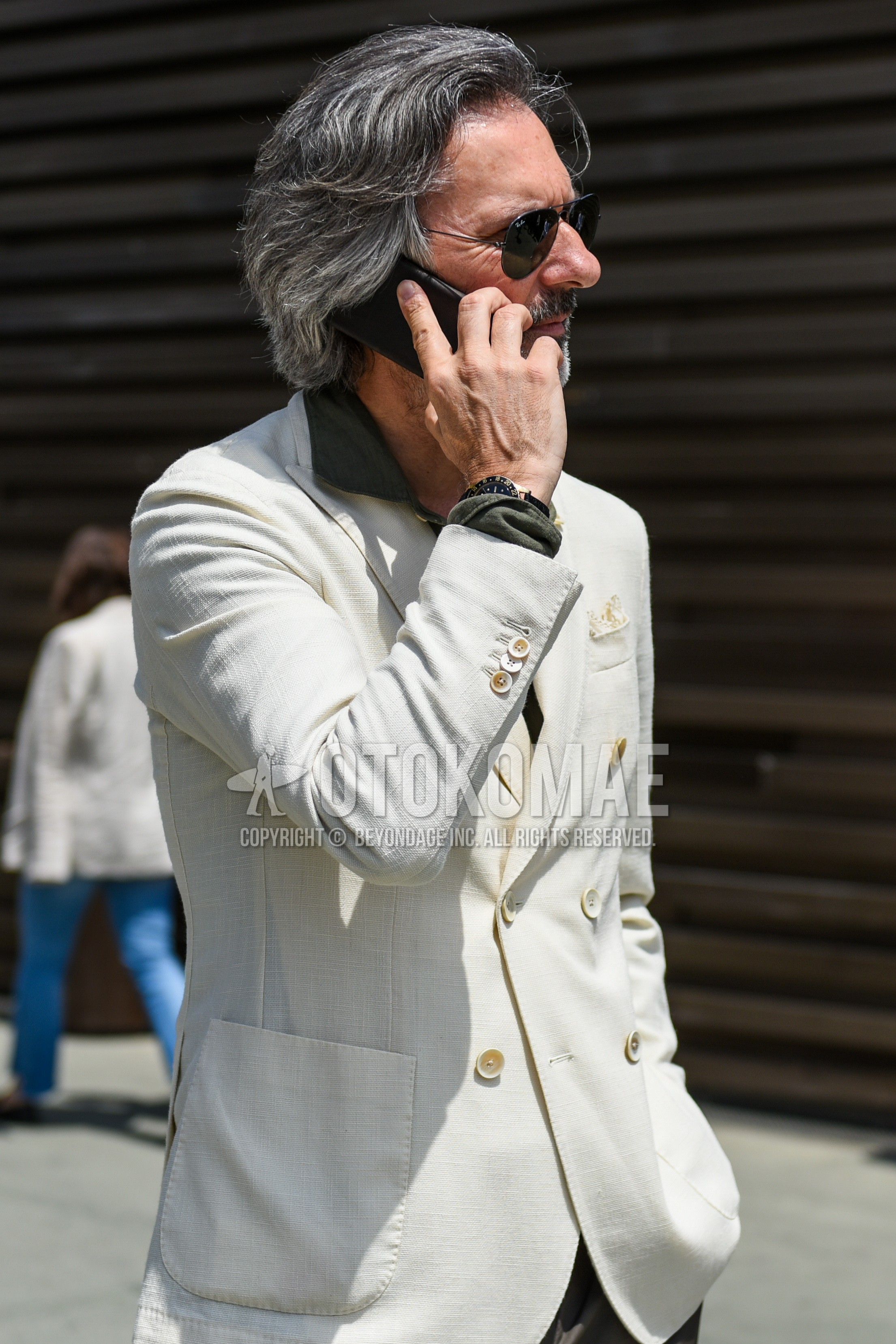 Men's spring summer outfit with black plain sunglasses, white plain tailored jacket, olive green plain shirt.