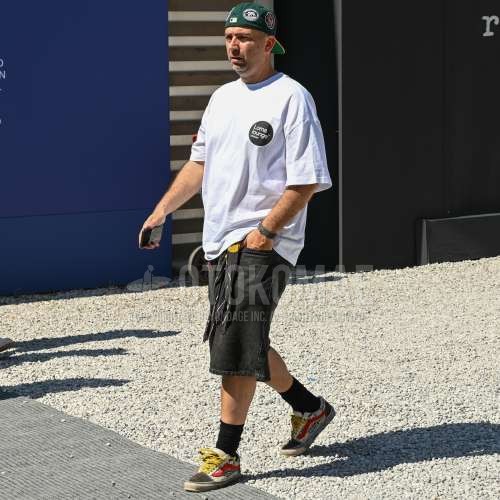 グリーンキャップのベースボールキャップ、黒ストールのバンダナ/ネッカチーフ、白ワンポイントのTシャツ、黒無地のショートパンツ、黒無地のデニム/ジーンズ、黒無地のソックス、白ローカットのスニーカーを合わせた夏のメンズコーデ・着こなし。