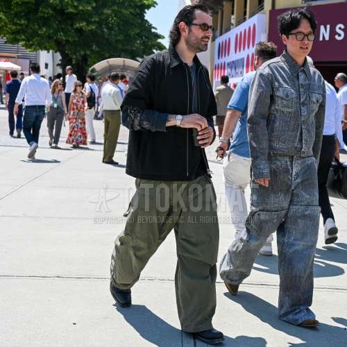 黒無地のサングラス、黒無地のアウター、グレー無地のロンT、オリーブグリーン無地のカーゴパンツ、黒のブーツを合わせた春夏のメンズコーデ・着こなし。