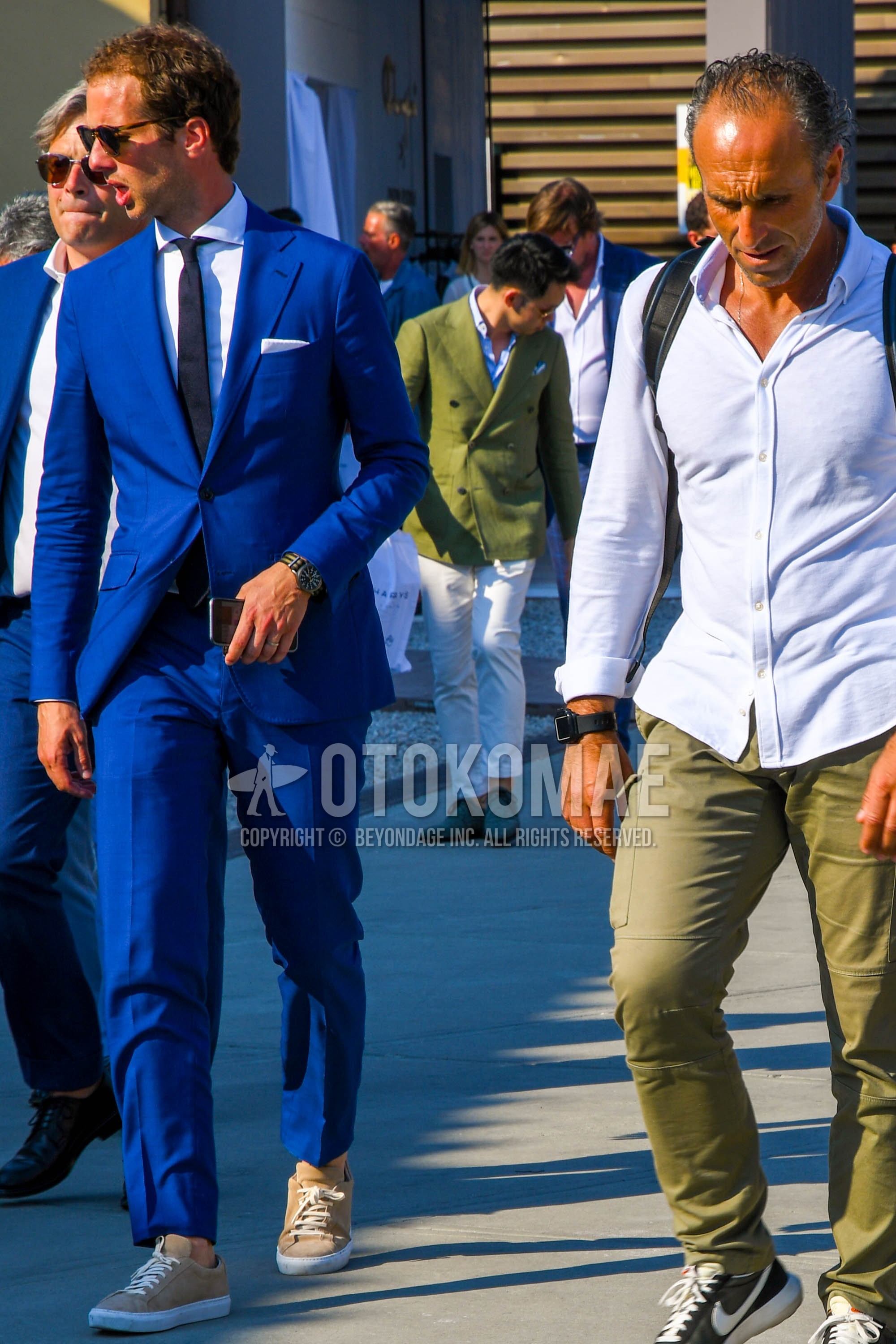 Men's spring summer autumn outfit with plain sunglasses, white plain shirt, beige low-cut sneakers, blue plain suit, navy plain necktie.