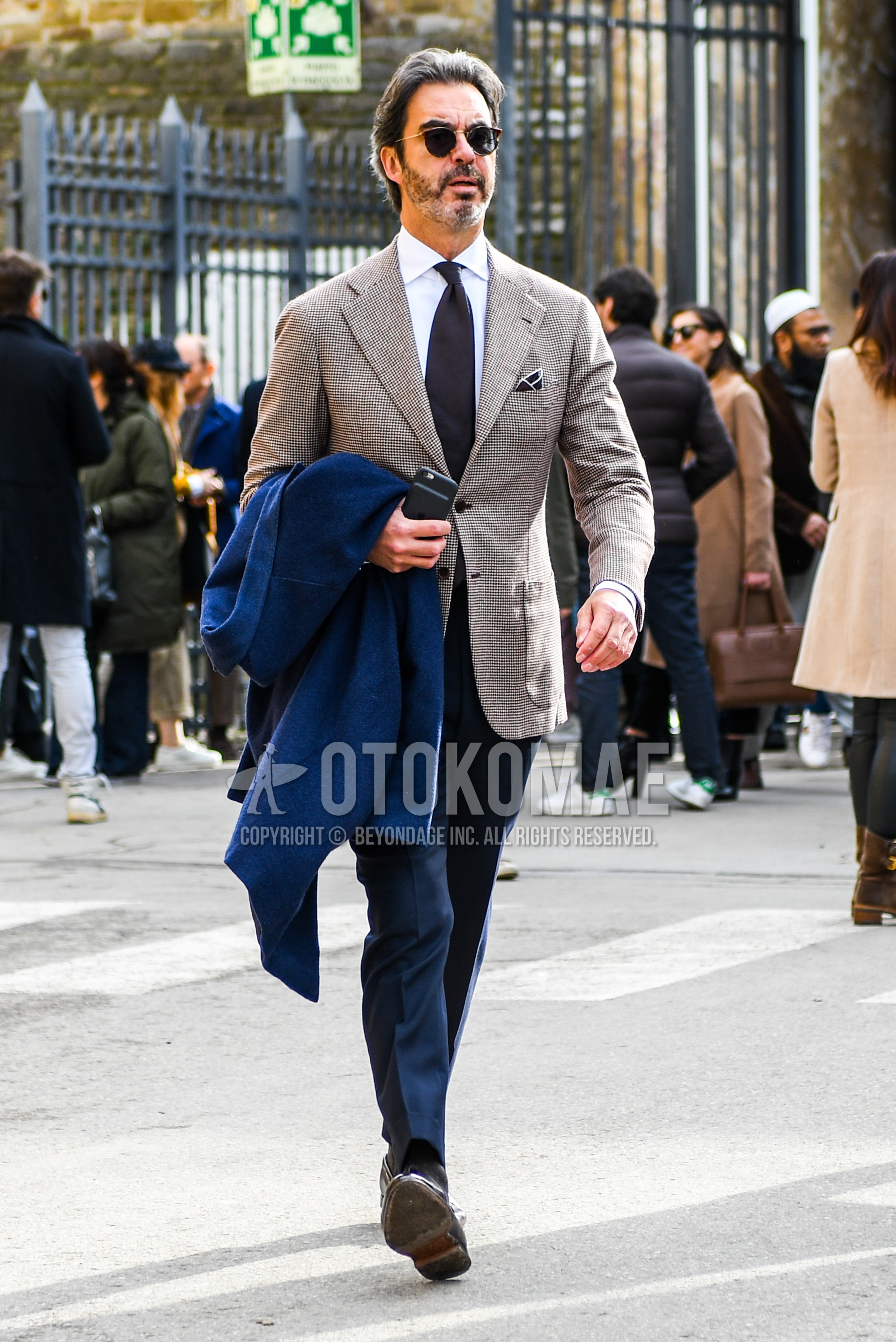 Men's spring autumn outfit with plain sunglasses, brown check tailored jacket, white plain shirt, gray plain slacks, brown plain necktie.