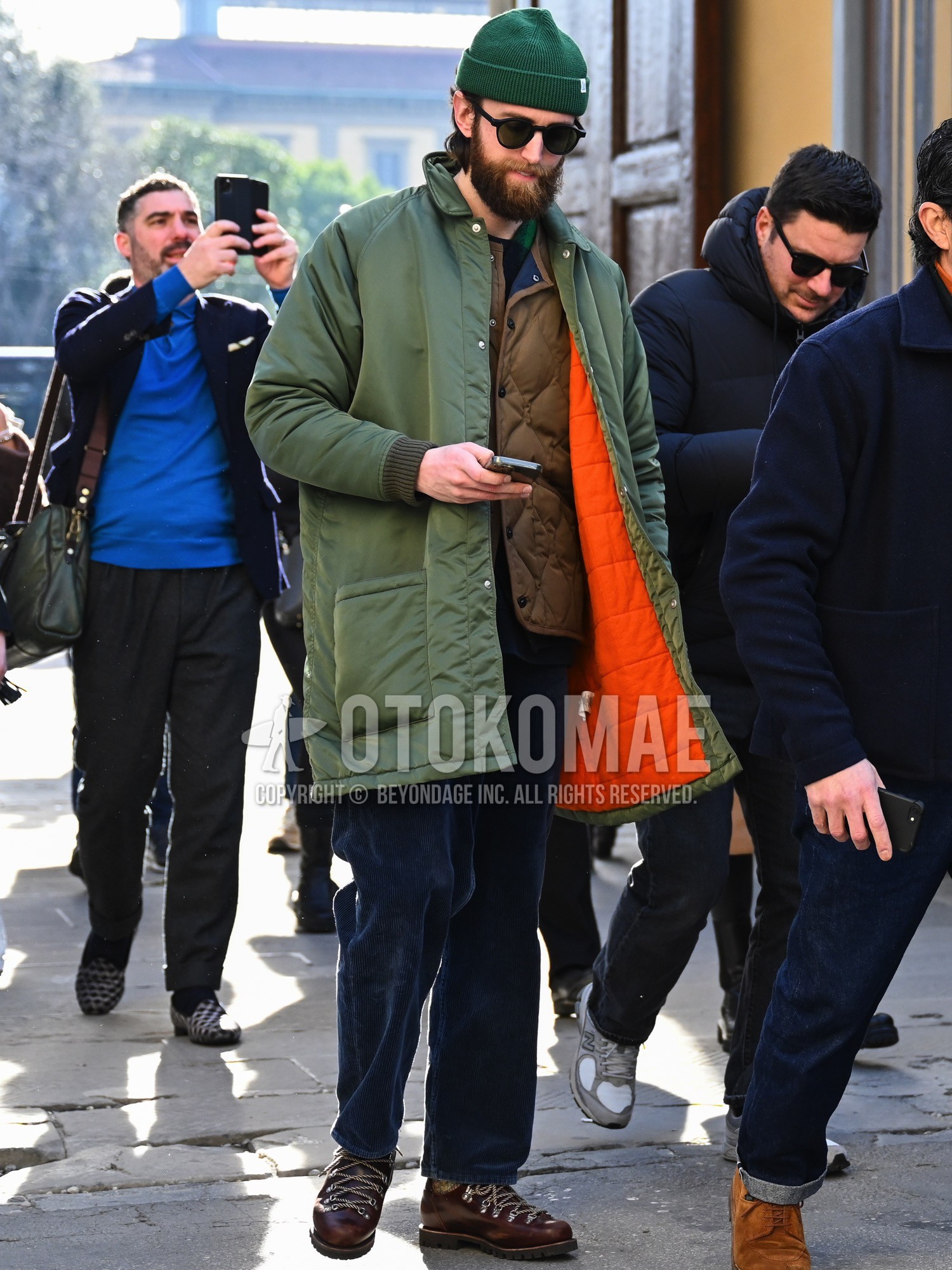 Men's autumn winter outfit with green plain knit cap, black plain sunglasses, olive green plain stenkarrer coat, brown plain inner down, navy plain winter pants (corduroy,velour), brown work boots.