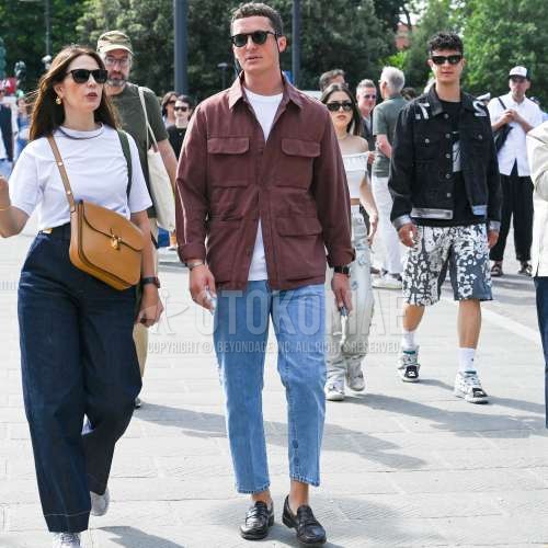 黒無地のサングラス、ブラウン無地のM-65、白無地のTシャツ、水色無地のデニム/ジーンズ、黒コインローファーの革靴を合わせた春秋のメンズコーデ・着こなし。