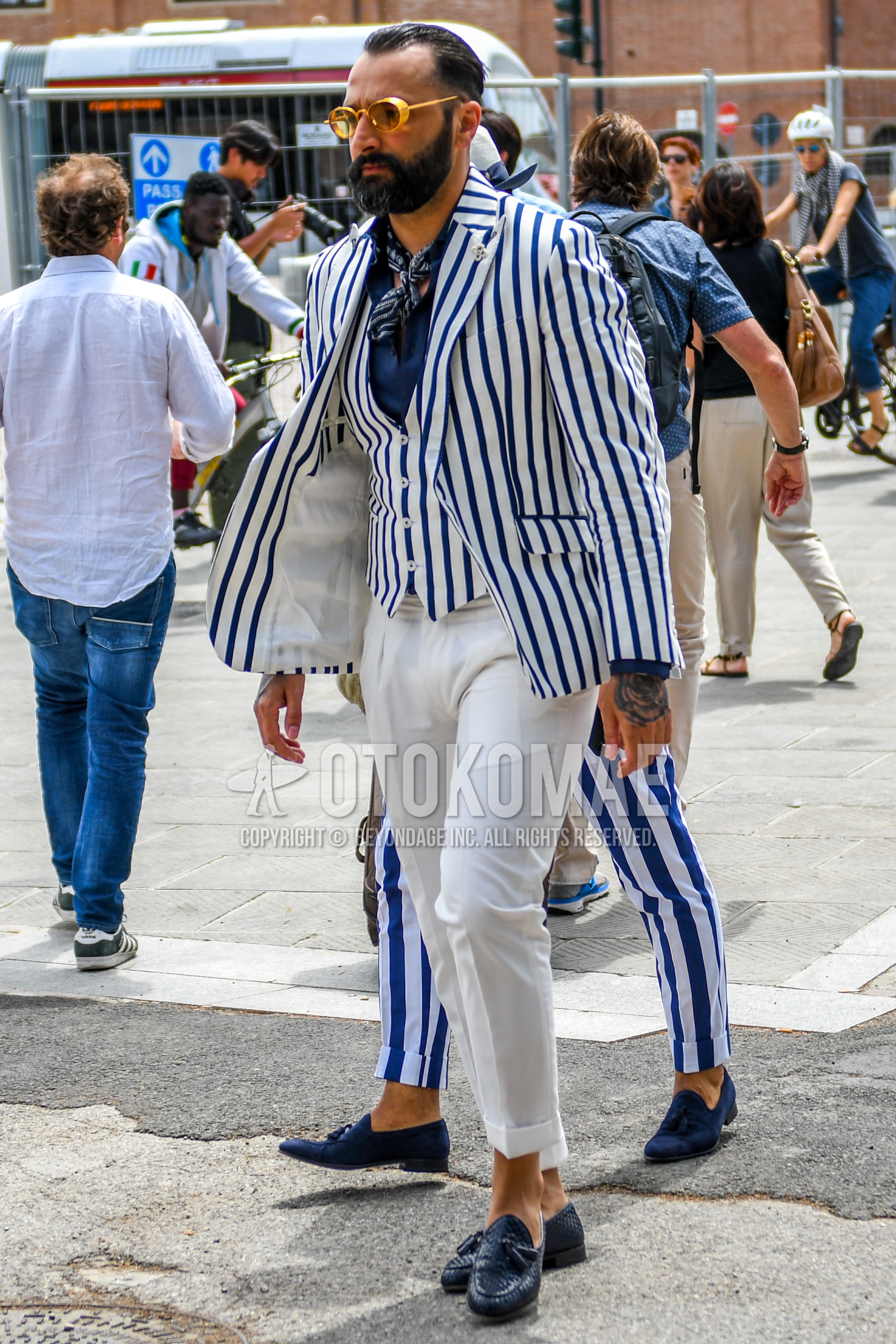 Men's spring summer autumn outfit with plain glasses, navy scarf bandana/neckerchief, navy white stripes tailored jacket, blue plain shirt, navy white stripes gilet, white plain slacks, navy tassel loafers leather shoes.