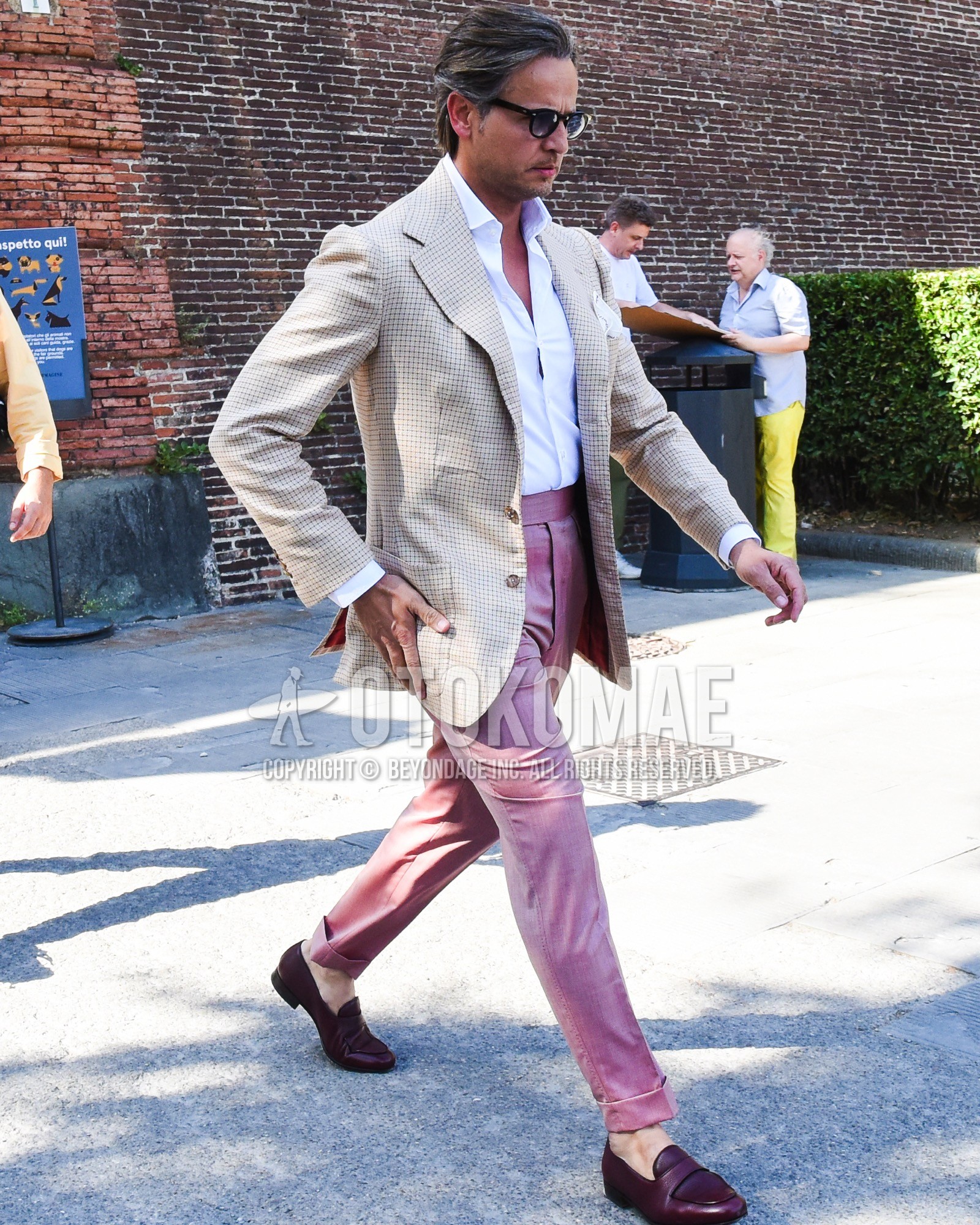 Men's spring summer outfit with black plain sunglasses, beige check tailored jacket, white plain shirt, pink plain slacks, red  loafers leather shoes.