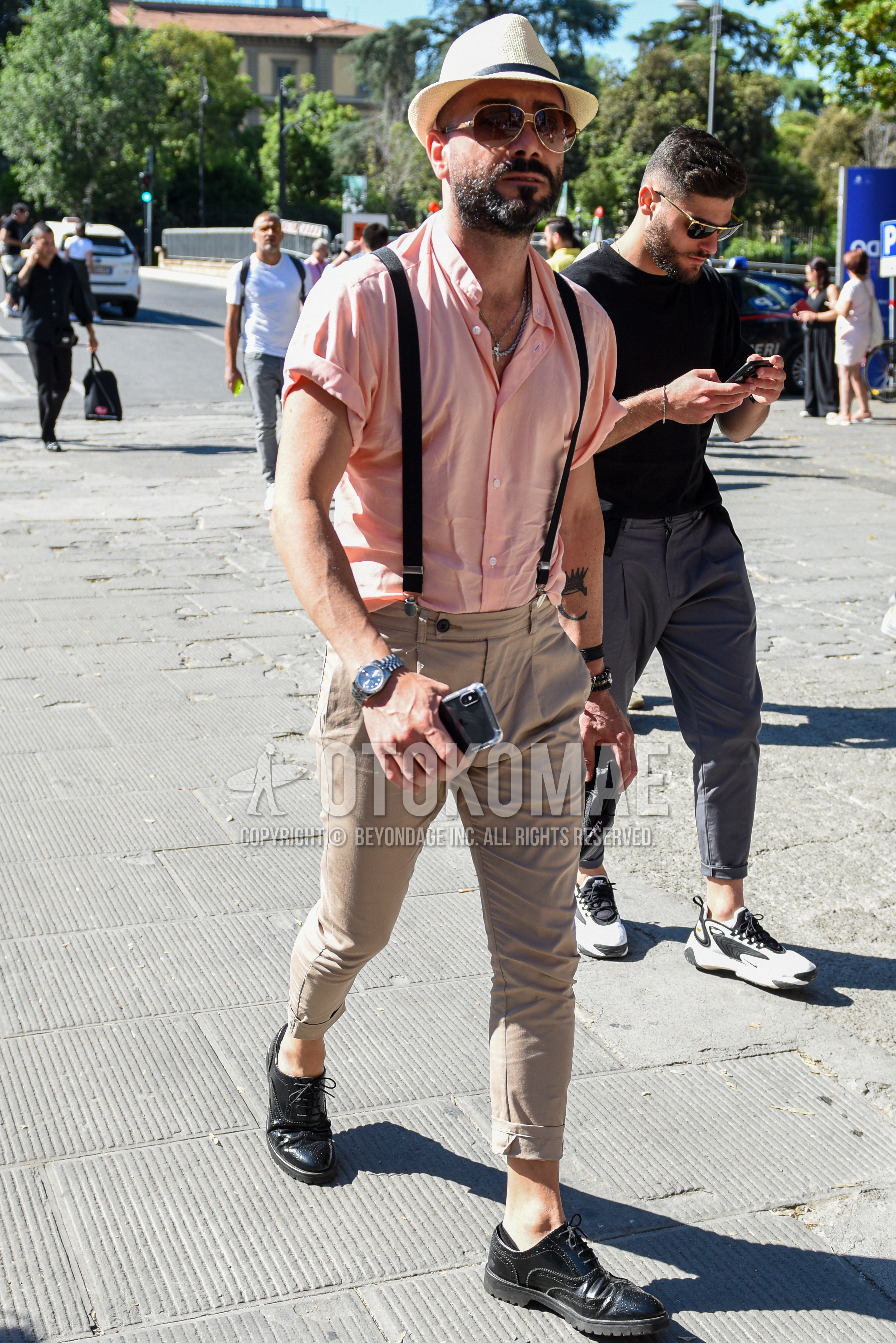 Men's summer outfit with beige plain hat, gold brown plain sunglasses, orange plain shirt, black plain suspenders, beige plain chinos, black wing-tip shoes leather shoes.