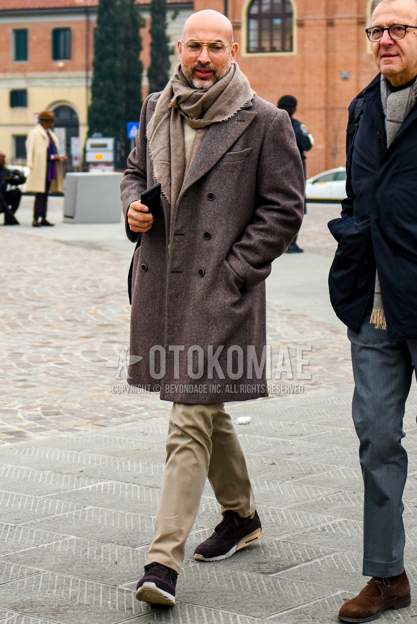 Men's winter outfit with plain glasses, brown plain scarf, brown plain chester coat, brown plain cotton pants, brown low-cut sneakers.