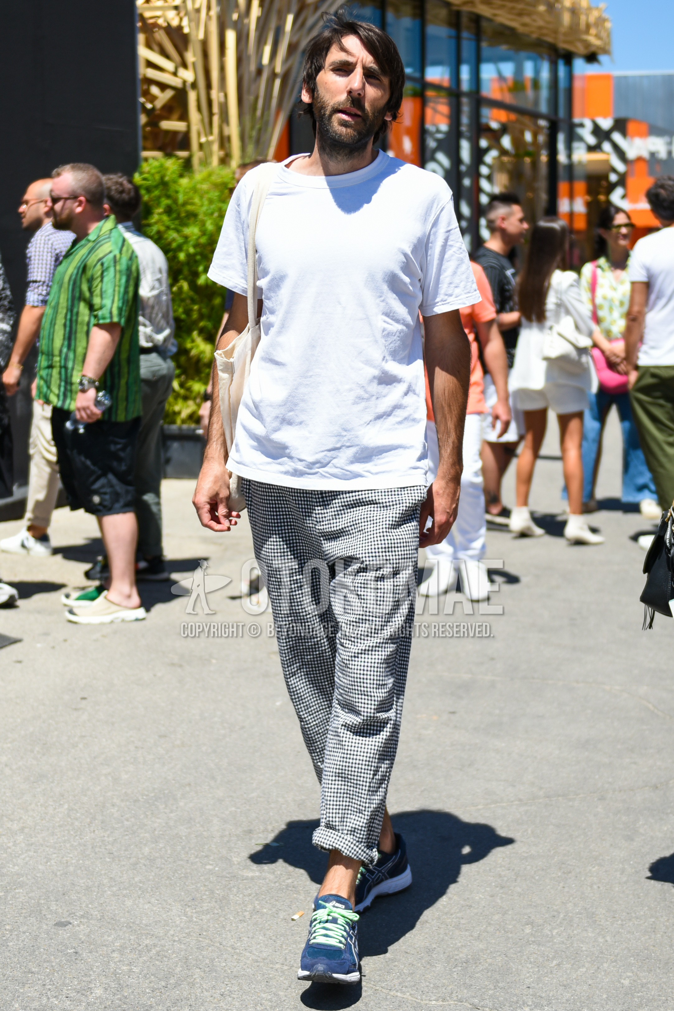 Men's summer outfit with white plain t-shirt, gray check cotton pants, blue low-cut sneakers, beige plain tote bag.