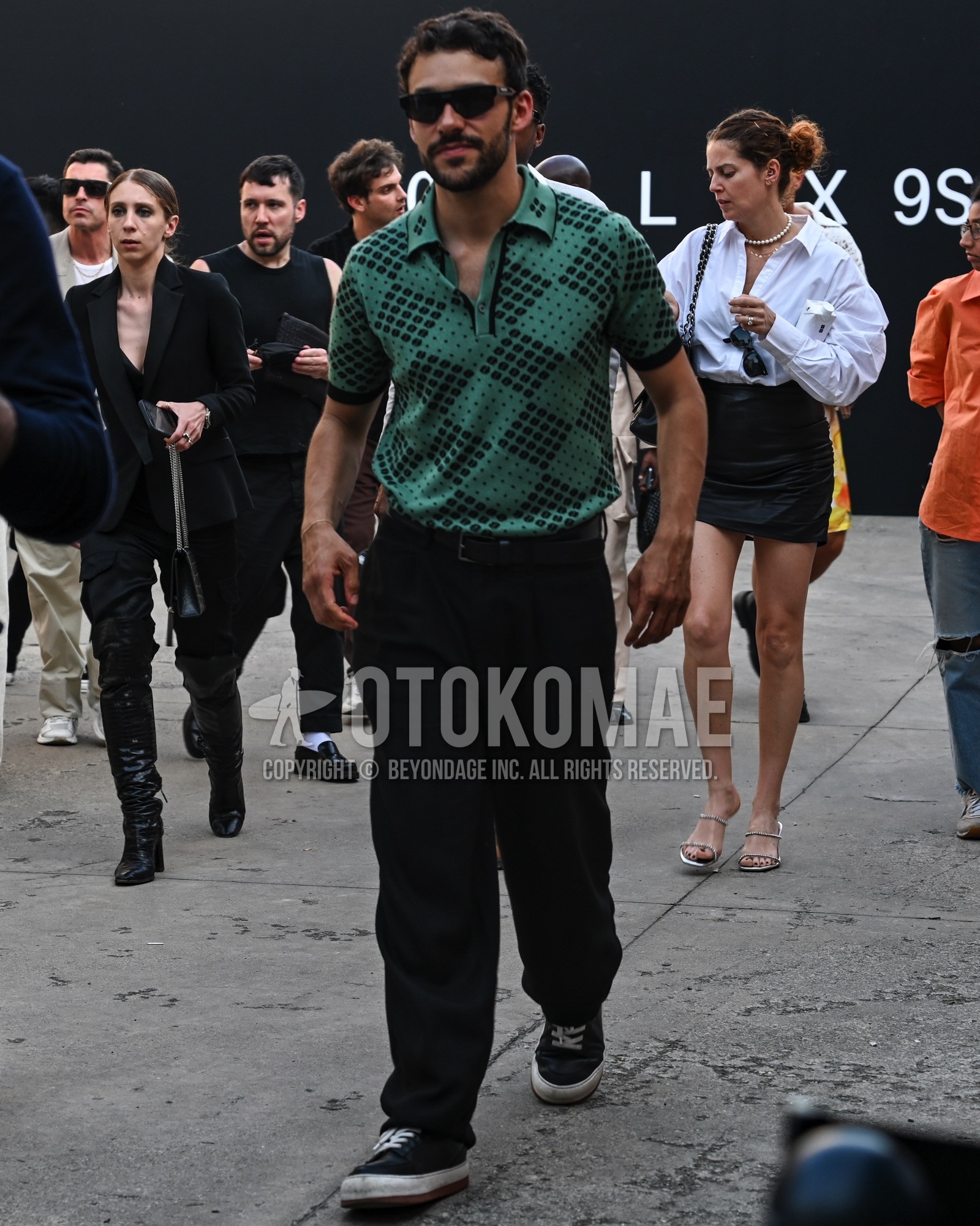 Men's spring summer outfit with black plain sunglasses, green check polo shirt, black plain wide pants, black low-cut sneakers.
