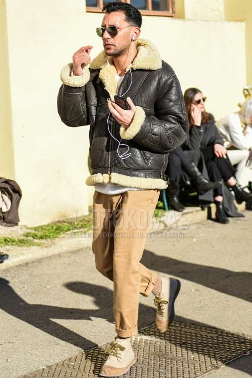 ティアドロップのゴールド無地のサングラス、黒無地のレザージャケット(ライダース以外)、黒無地のミリタリージャケット(MA-1、M-65以外)、白無地のセーター、ベージュ無地のチノパン、ベージュ無地のソックス、ベージュハイカットのスニーカーを合わせた冬のメンズコーデ・着こなし。