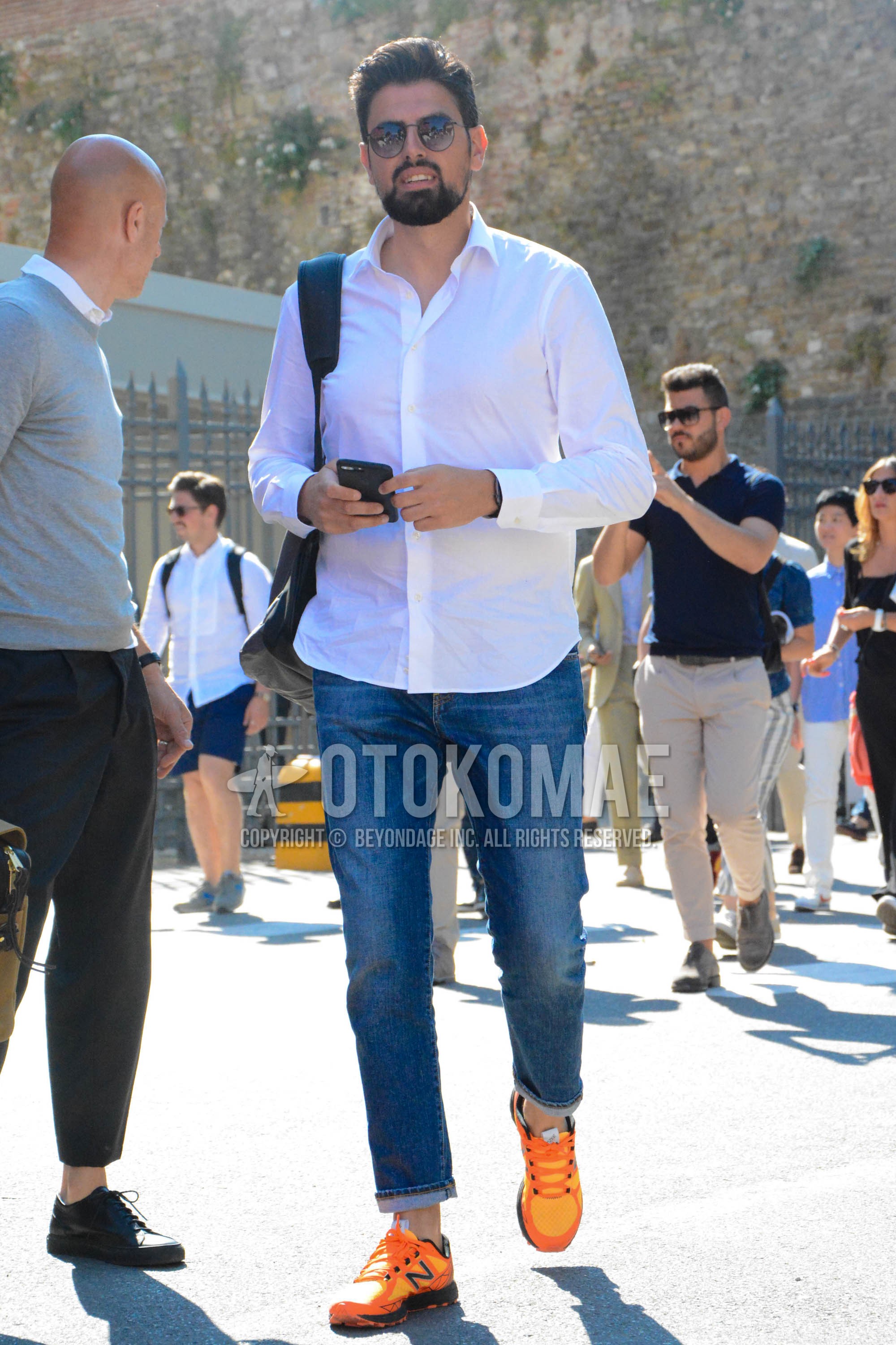 Men's spring summer outfit with plain sunglasses, white plain shirt, blue plain denim/jeans, orange low-cut sneakers.