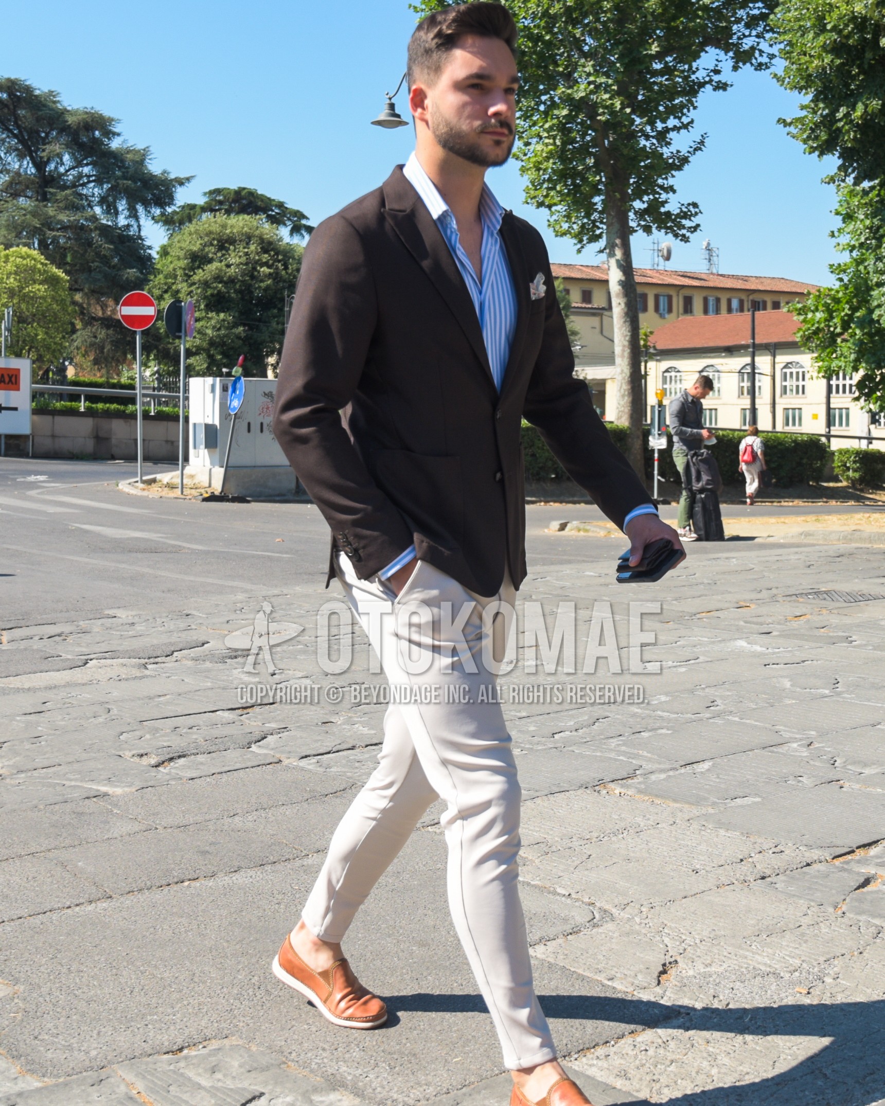 Men's spring summer autumn outfit with brown plain tailored jacket, blue stripes shirt, white plain cotton pants, brown slip-on sneakers, brown  leather shoes.