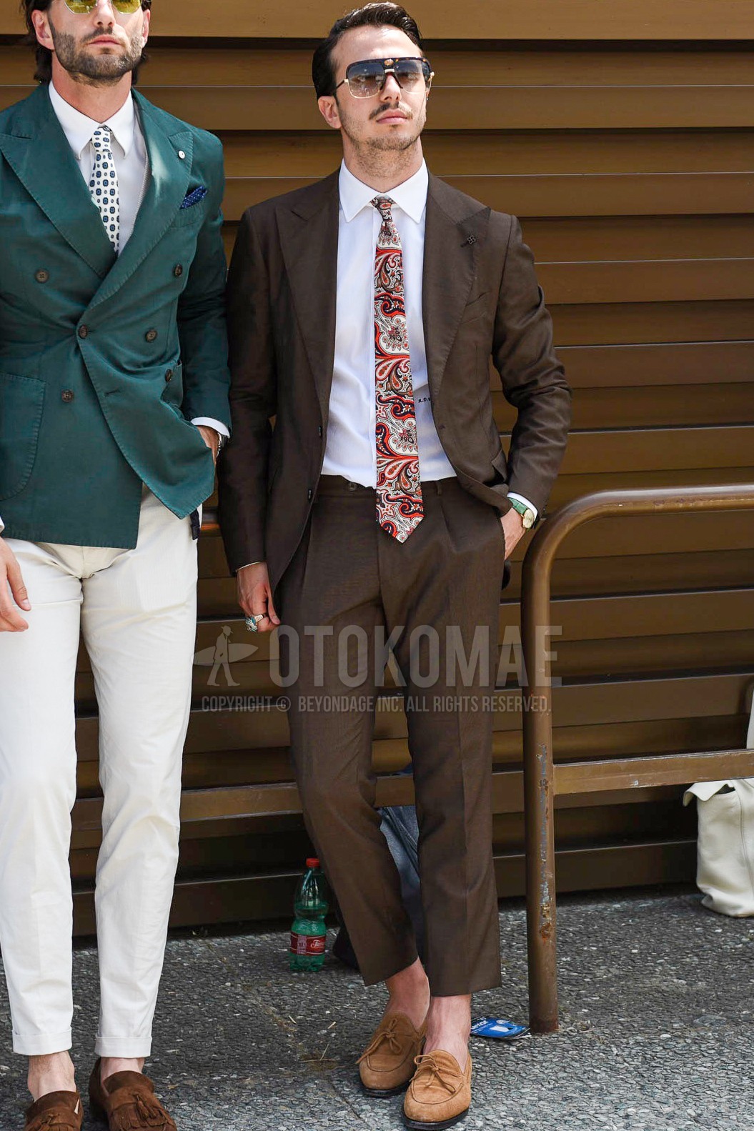 Men's spring summer autumn outfit with black plain sunglasses, white plain shirt, brown moccasins/deck shoes leather shoes, brown plain suit, red paisley necktie.