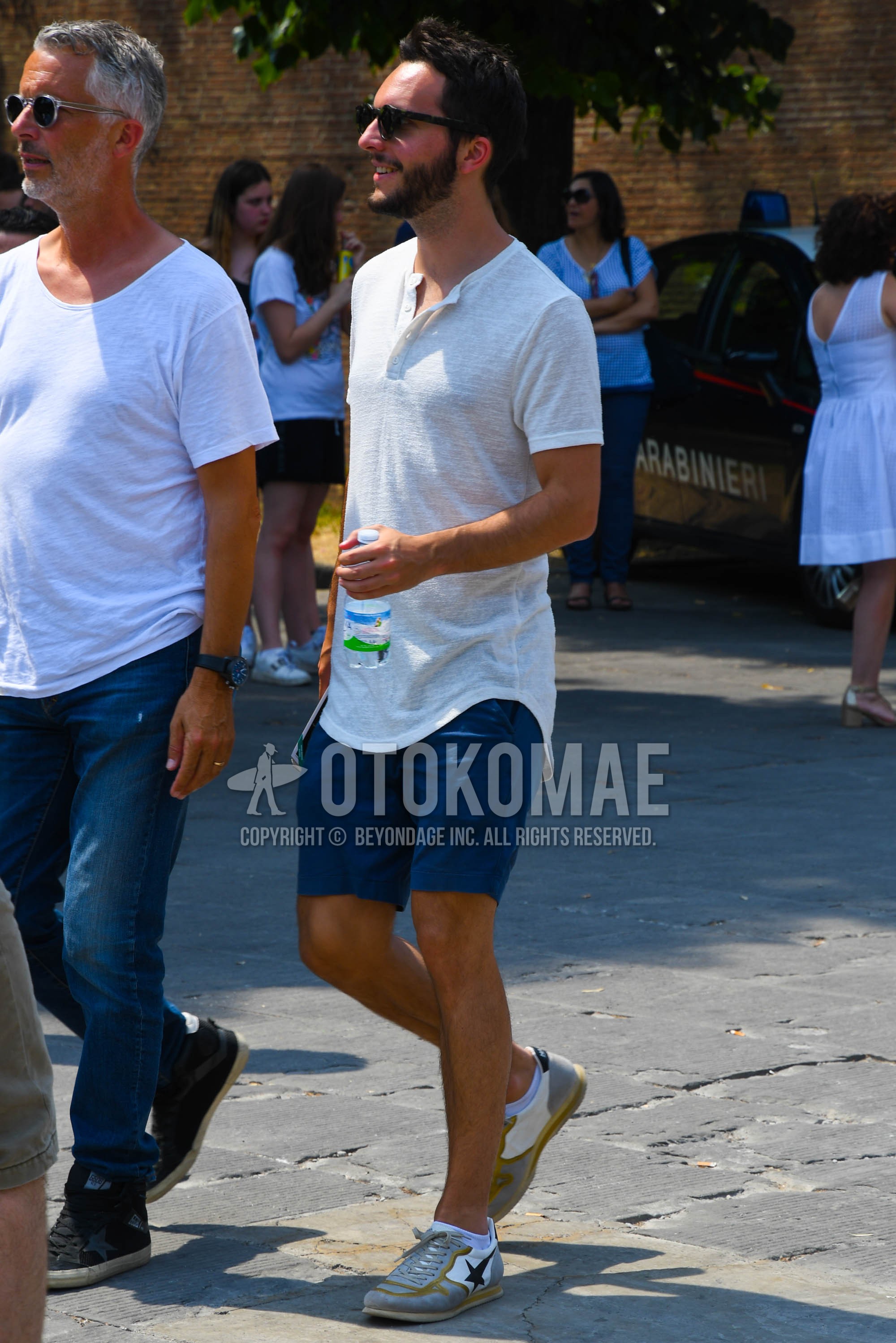 Men's summer outfit with plain sunglasses, white plain t-shirt, blue plain short pants, plain chinos, white low-cut sneakers.