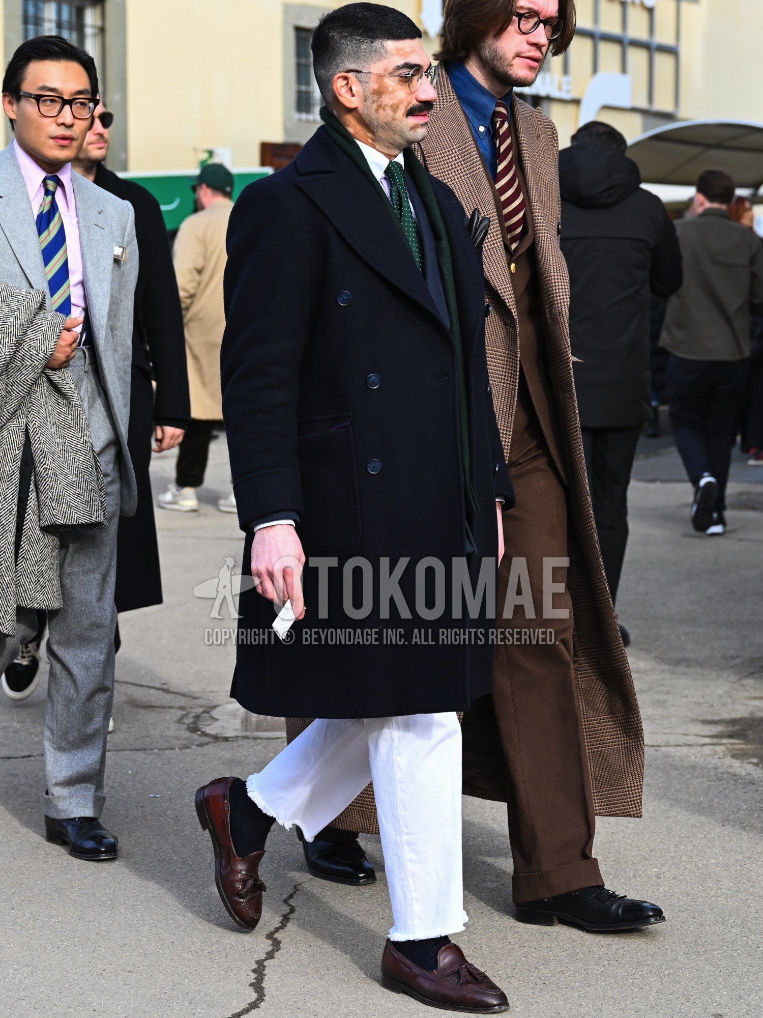 Men's autumn winter outfit with silver plain glasses, green plain scarf, navy plain chester coat, white plain shirt, navy plain tailored jacket, white plain denim/jeans, navy plain socks, brown tassel loafers leather shoes, green dots necktie.