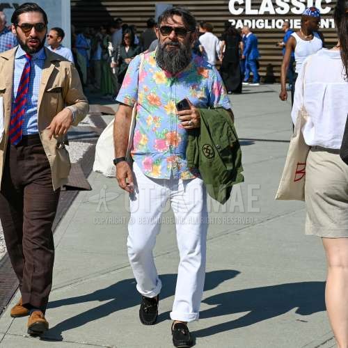 ブラウンべっ甲のサングラス、グリーン無地のアウター、ブルー総柄のシャツ、白無地のチノパン、黒ローファーの革靴、黒スエードシューズの革靴、白無地のトートバッグを合わせた春夏のメンズコーデ・着こなし。