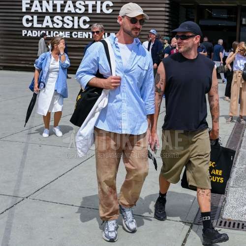 白無地のベースボールキャップ、黒無地のサングラス、ブルーストライプのシャツ、白無地のTシャツ、ベージュボトムスのジョガーパンツ/リブパンツ、ベージュボトムスのチノパン、白ローカットのスニーカー、黒レタードのトートバッグ、白無地のトートバッグを合わせた夏春のメンズコーデ・着こなし。