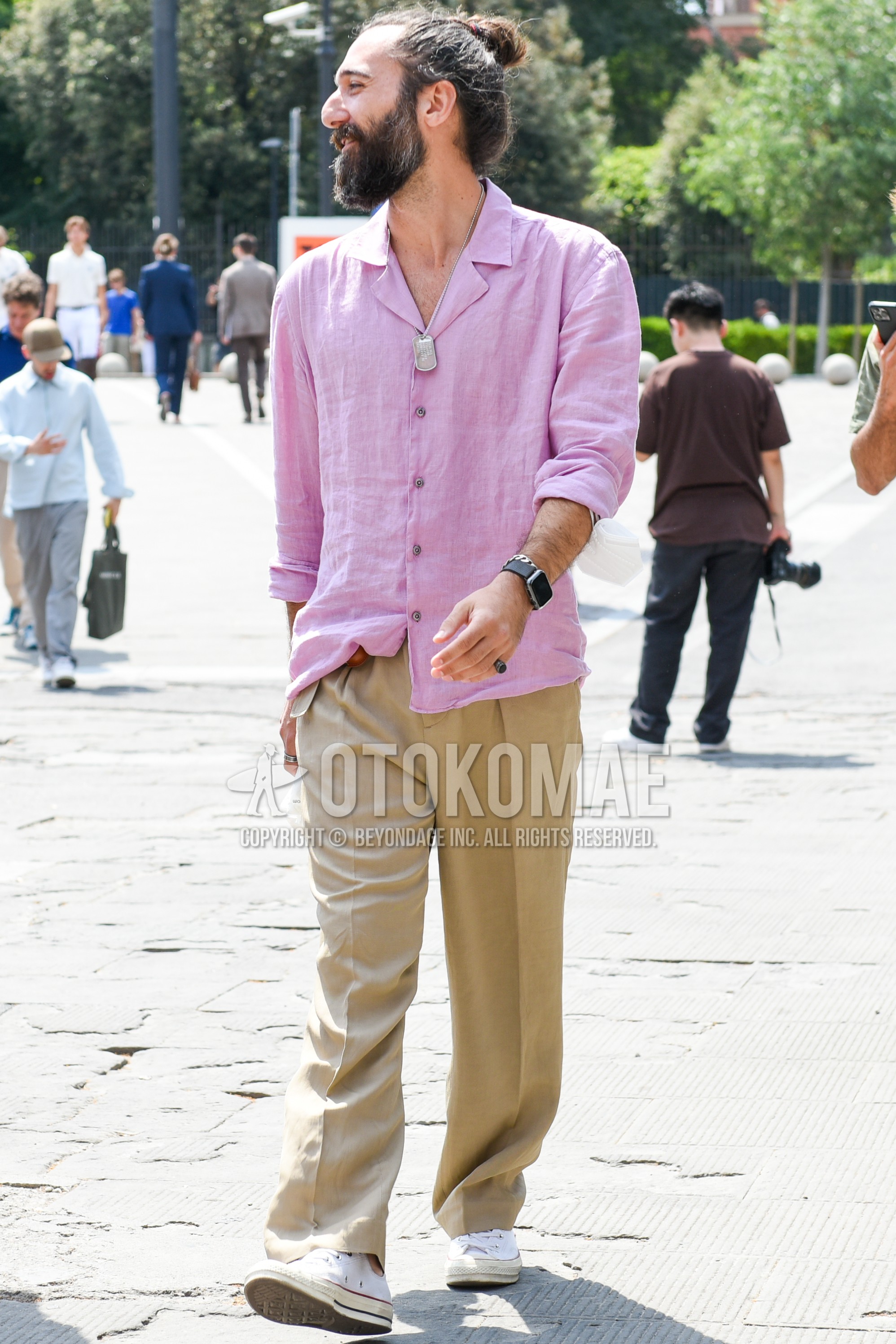 Men's spring summer autumn outfit with pink plain shirt, beige plain slacks, white low-cut sneakers.