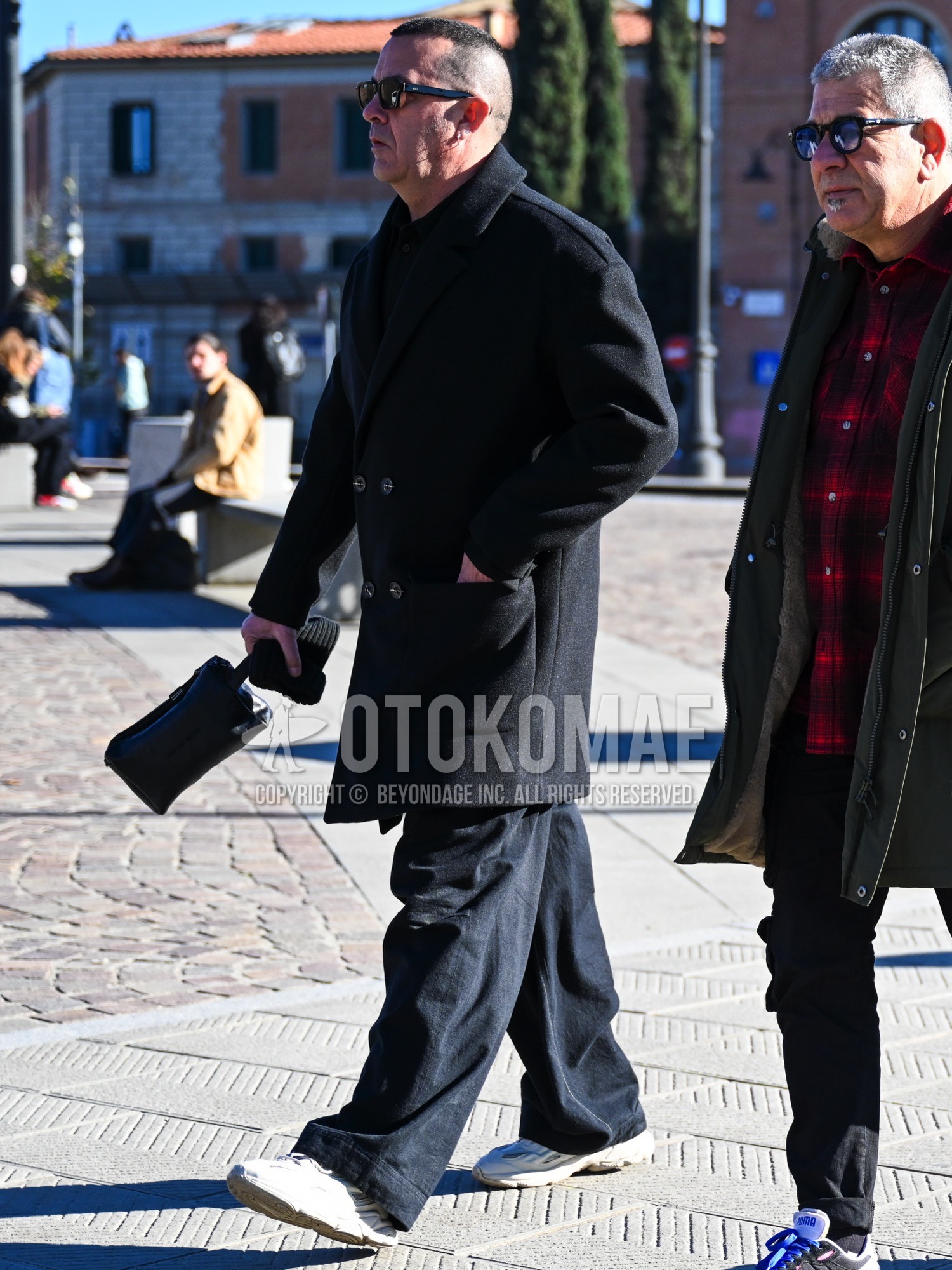 Men's autumn winter outfit with black plain sunglasses, black plain chester coat, black plain shirt, black plain slacks, white low-cut sneakers.
