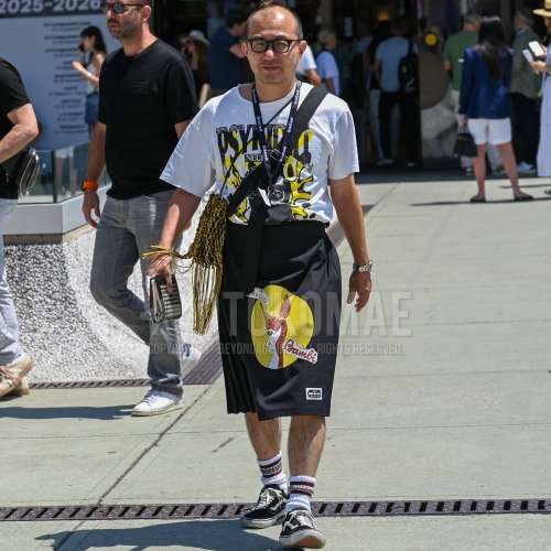 黒無地のメガネ、白グラフィックのTシャツ、黒グラフィックのショートパンツ、白ソックスのソックス、ヴァンズ　オールドスクールの黒ローカットのスニーカー、イエローバッグのショルダーバッグを合わせた夏のメンズコーデ・着こなし。