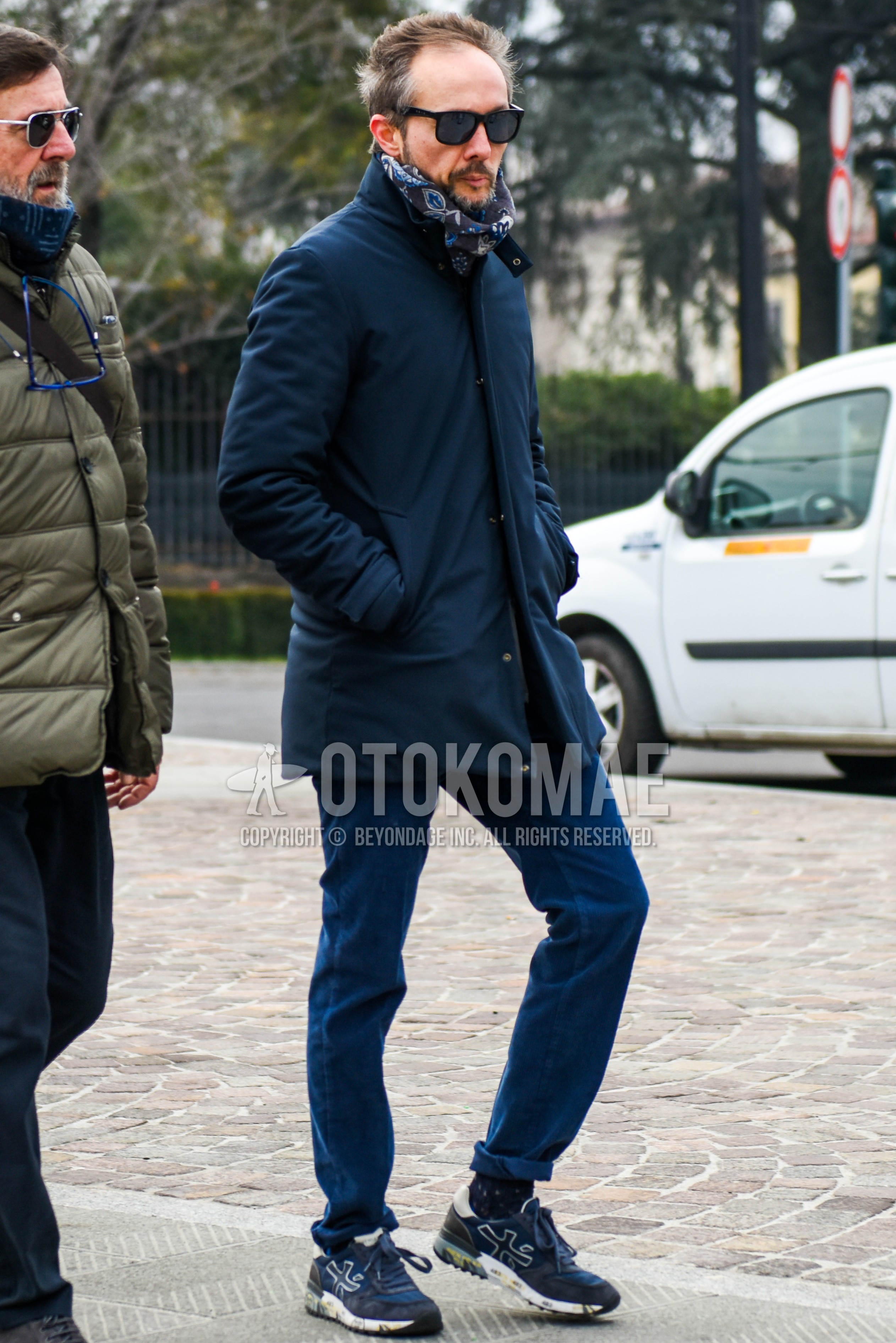 Men's autumn winter outfit with black plain sunglasses, brown scarf scarf, navy plain stenkarrer coat, navy plain chinos, black socks socks, navy low-cut sneakers.