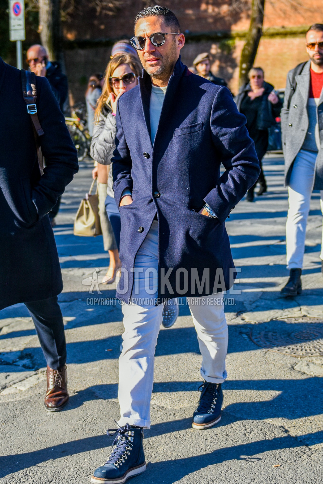 Men's autumn winter outfit with black plain sunglasses, navy plain chester coat, gray plain sweatshirt, white plain denim/jeans, navy work boots.