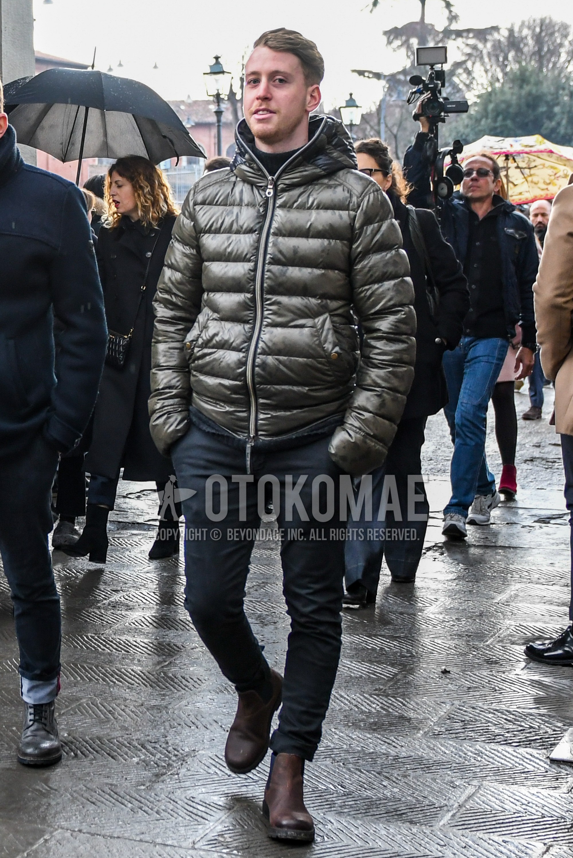 Men's winter outfit with olive green plain down jacket, black plain turtleneck knit, black plain chinos, brown side-gore boots.