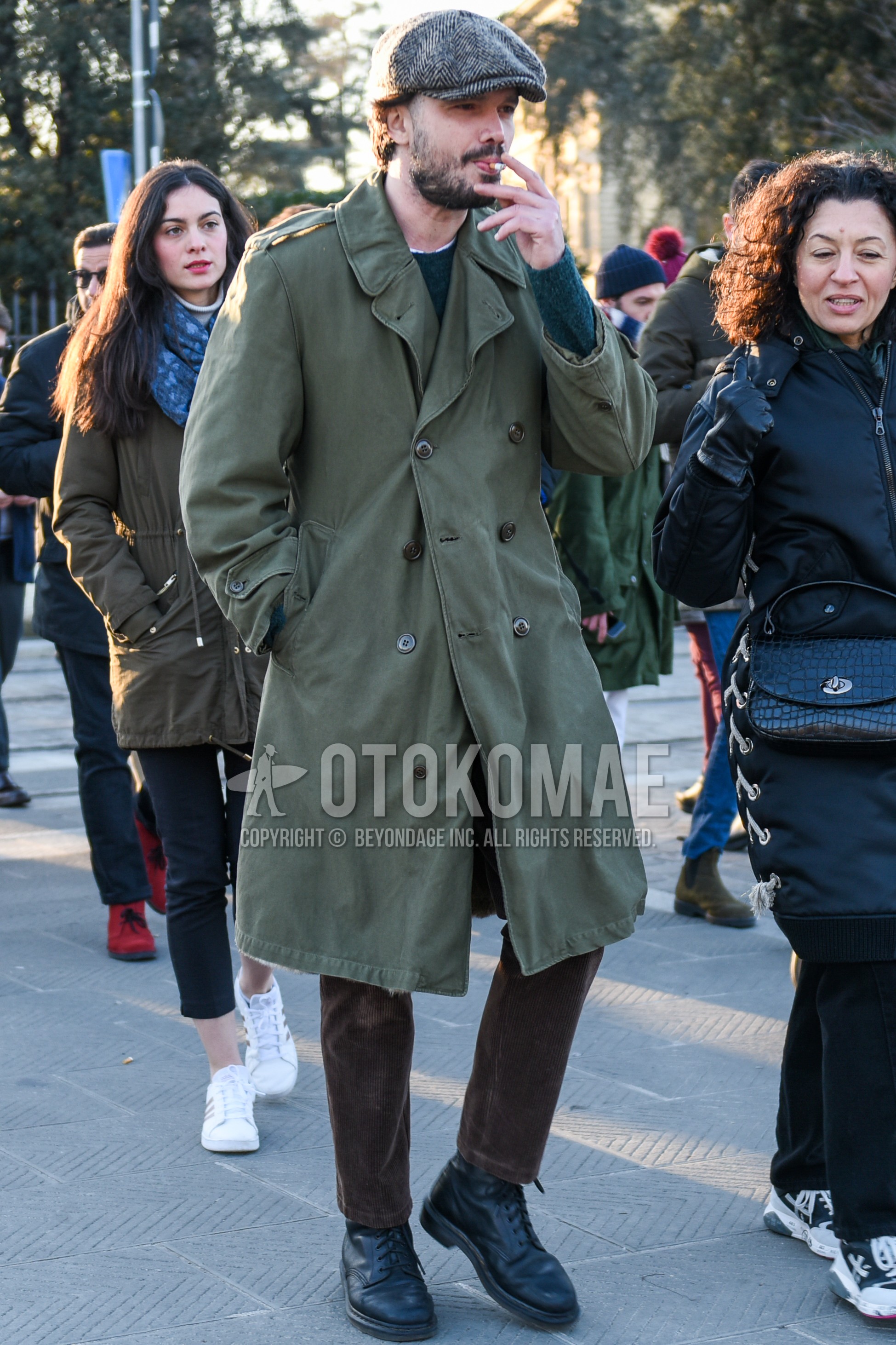 Men's autumn winter outfit with gray herringbone hunting cap, green plain trench coat, dark gray plain sweater, brown plain winter pants (corduroy,velour), brown plain cropped pants, black  boots.