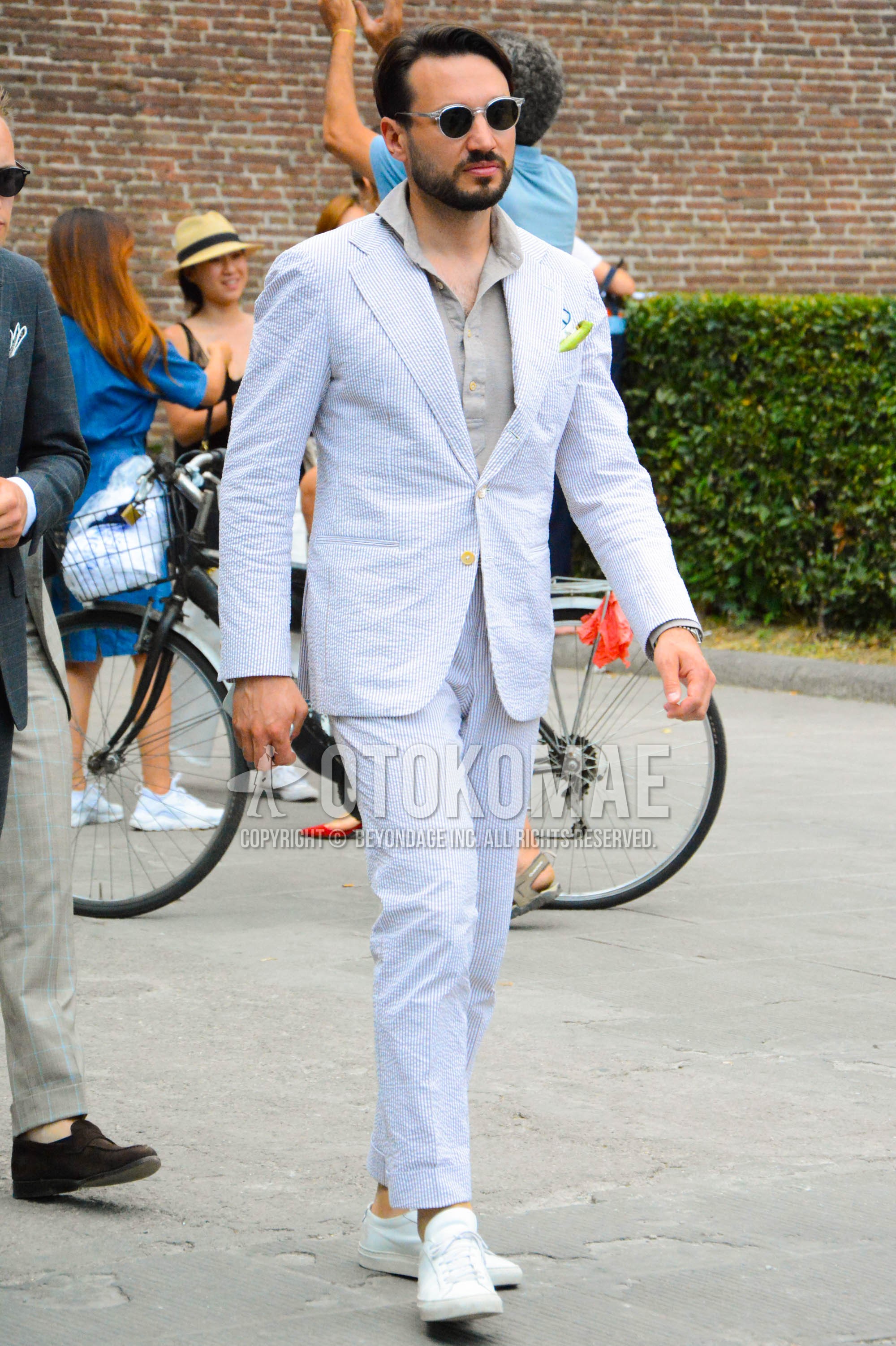 Men's spring summer autumn outfit with clear plain sunglasses, beige plain shirt, white low-cut sneakers, white stripes suit.