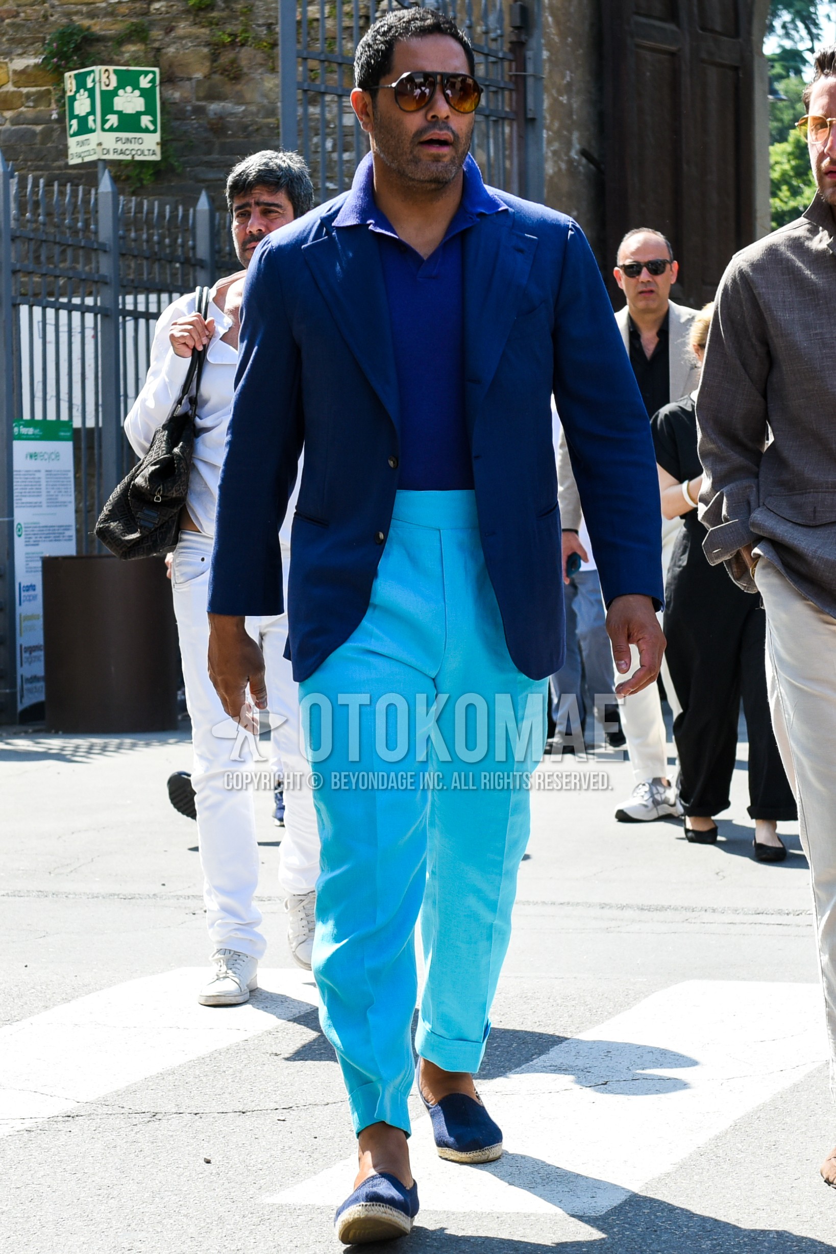 Men's spring summer autumn outfit with brown plain sunglasses, blue plain tailored jacket, blue plain polo shirt, light blue plain beltless pants, blue  espadrille.